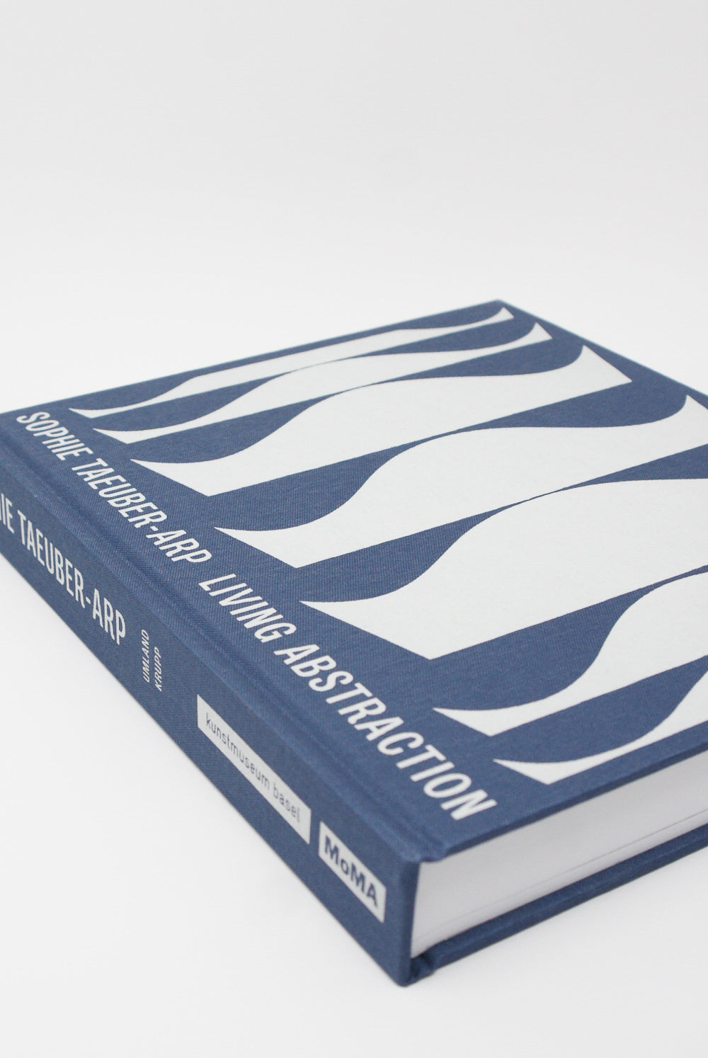 The cover of a Sophie Taeuber-Arp: Living Abstraction retrospective book with a blue and white design, published by Artbook/D.A.P.