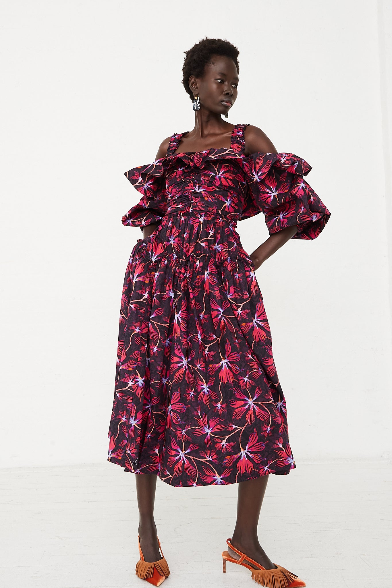 The model is wearing the Ulla Johnson Caprice Midi Dress in Zinnia, a patterned cotton poplin dress with vivid shades of magenta and hyacinth.