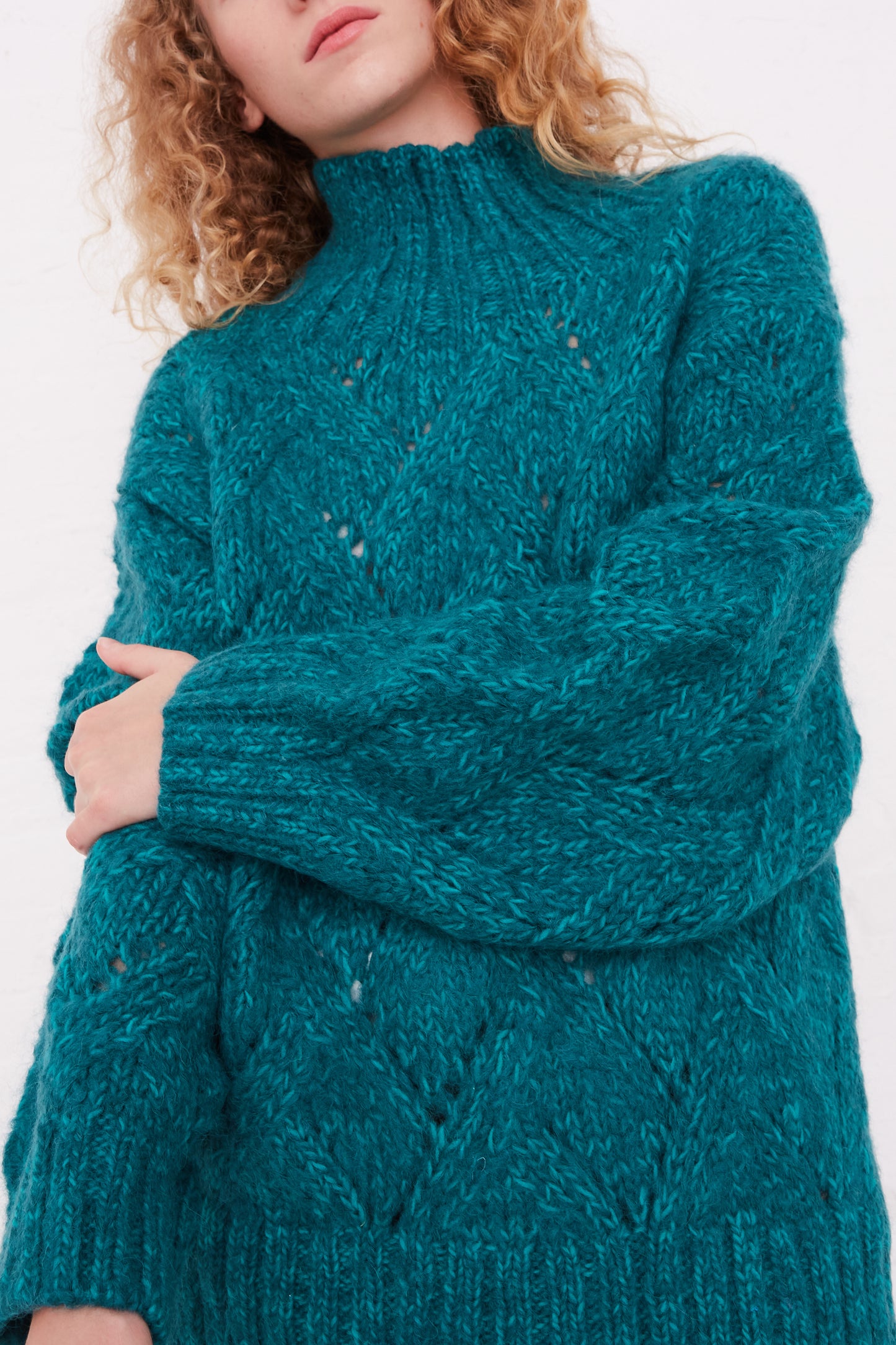 A woman wearing an Ichi Antiquités Hand-Knit Green Teal Wool and Alpaca Blend Turtleneck Sweater.