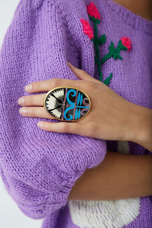 A woman wearing a purple sweater and Sofio Gongli ring with enamel decoration.