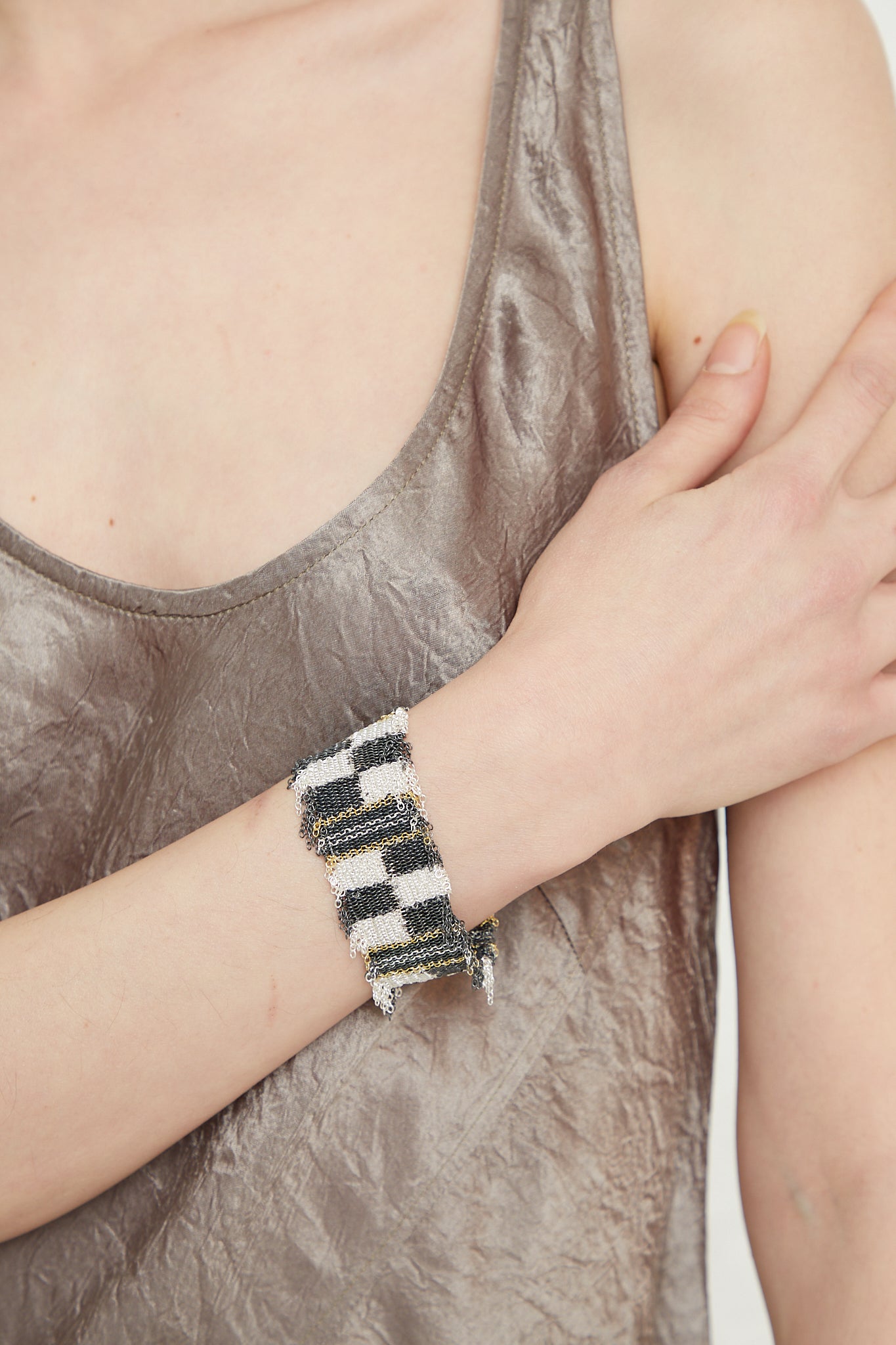 A woman wearing a silver tank top with a Stephanie Schneider Sterling Silver Oxidized Bracelet in Gold Plated and Silk.