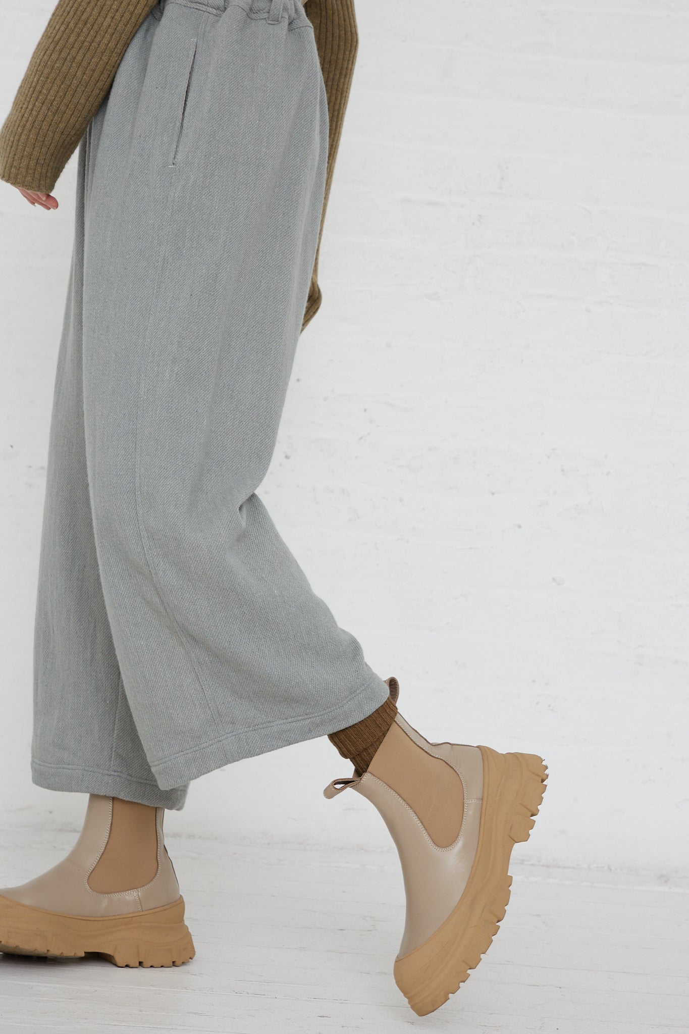 A woman wearing a beige Merino Wool Orihimedaki Pant in Blue by Ichi Antiquités and tan boots.