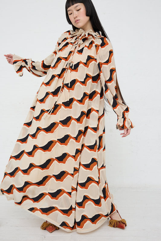 A woman in an Ulla Johnson Echo Dress in Conch, waving stripe devore.