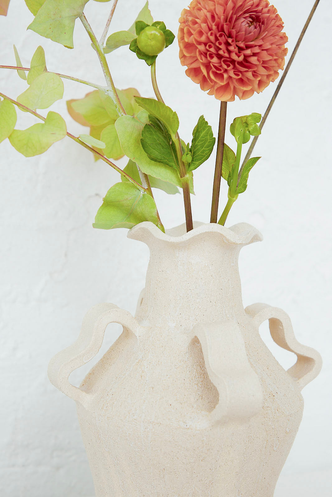 A Clandestine Amphora Peony Vase with flowers in it.
