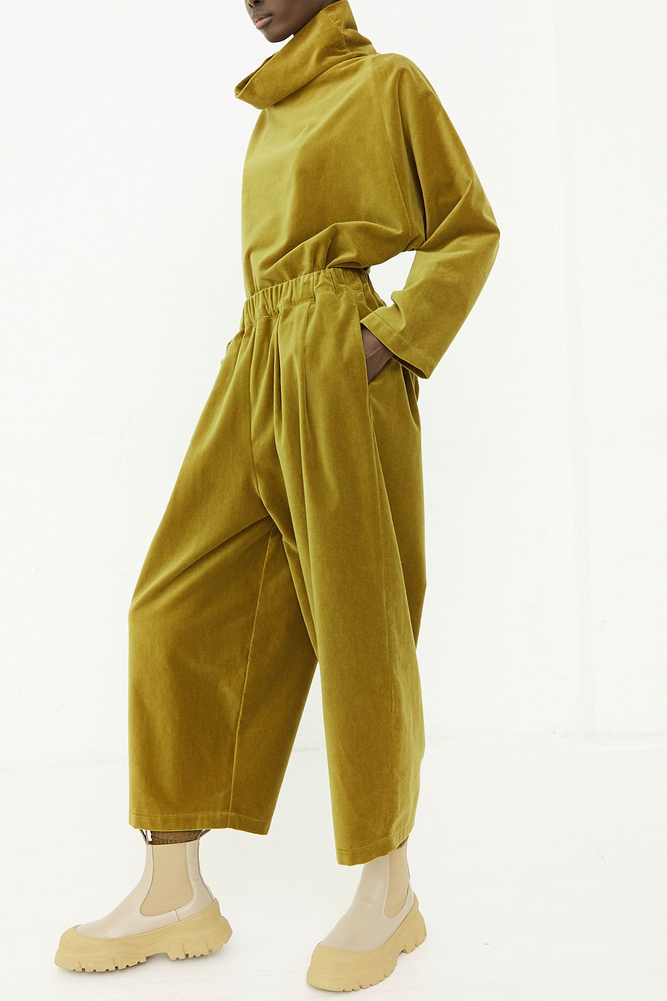 A woman wearing a yellow jumpsuit with an elasticated waist and wide leg pant design.