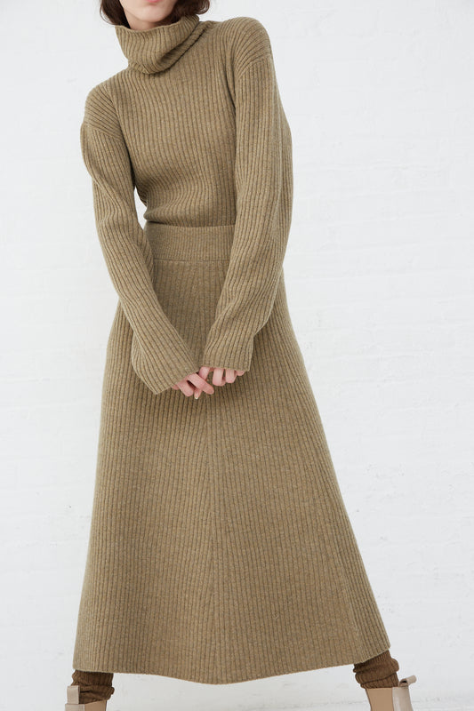 A woman wearing an Ichi Antiquités ribbed knit wool turtle neck sweater and a tan Ichi Antiquités midi skirt.