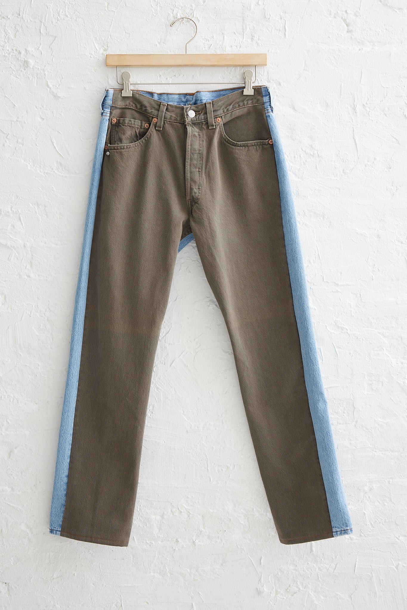 A pair of Bless Jeanspleatfront No. 73 in Surprise Color Mix A denim jeans with a mid-waist and 5-pocket design hanging on a wall.