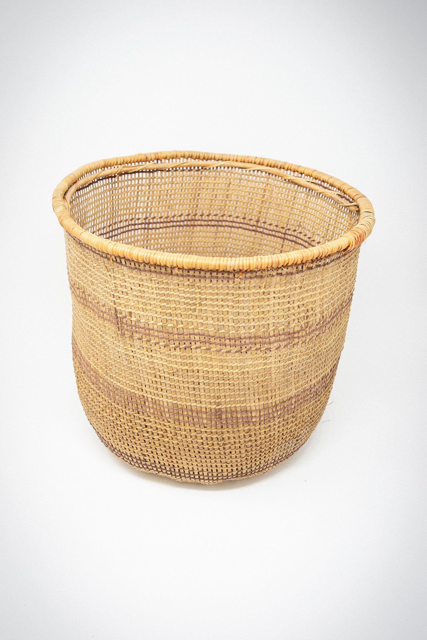 A Medium Nukak Makú basket beautifully handwoven with natural dyes on a white background by Plaza Bolivar.