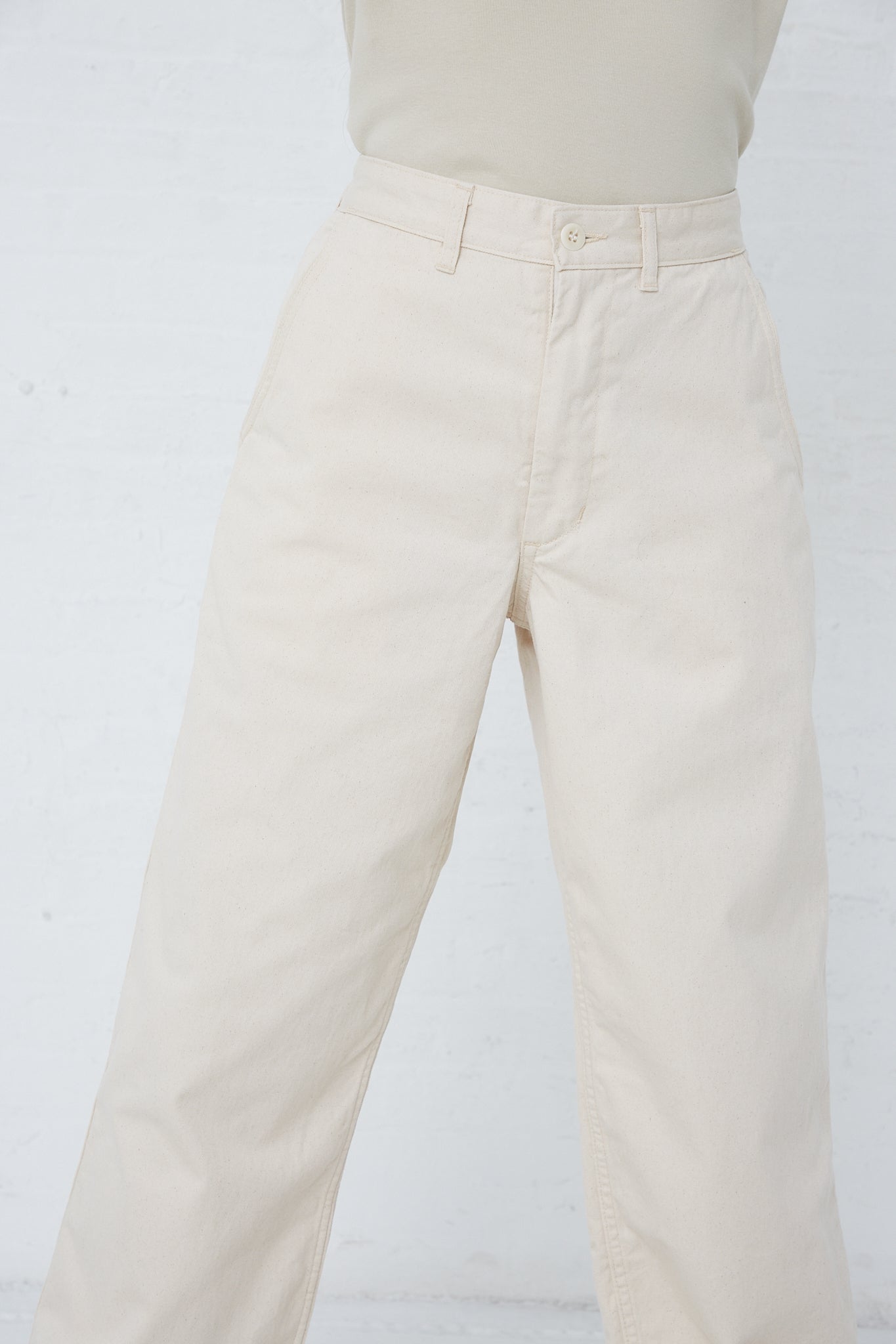 A woman donning As Ever's 51 Chino in Natural pants and a white shirt.