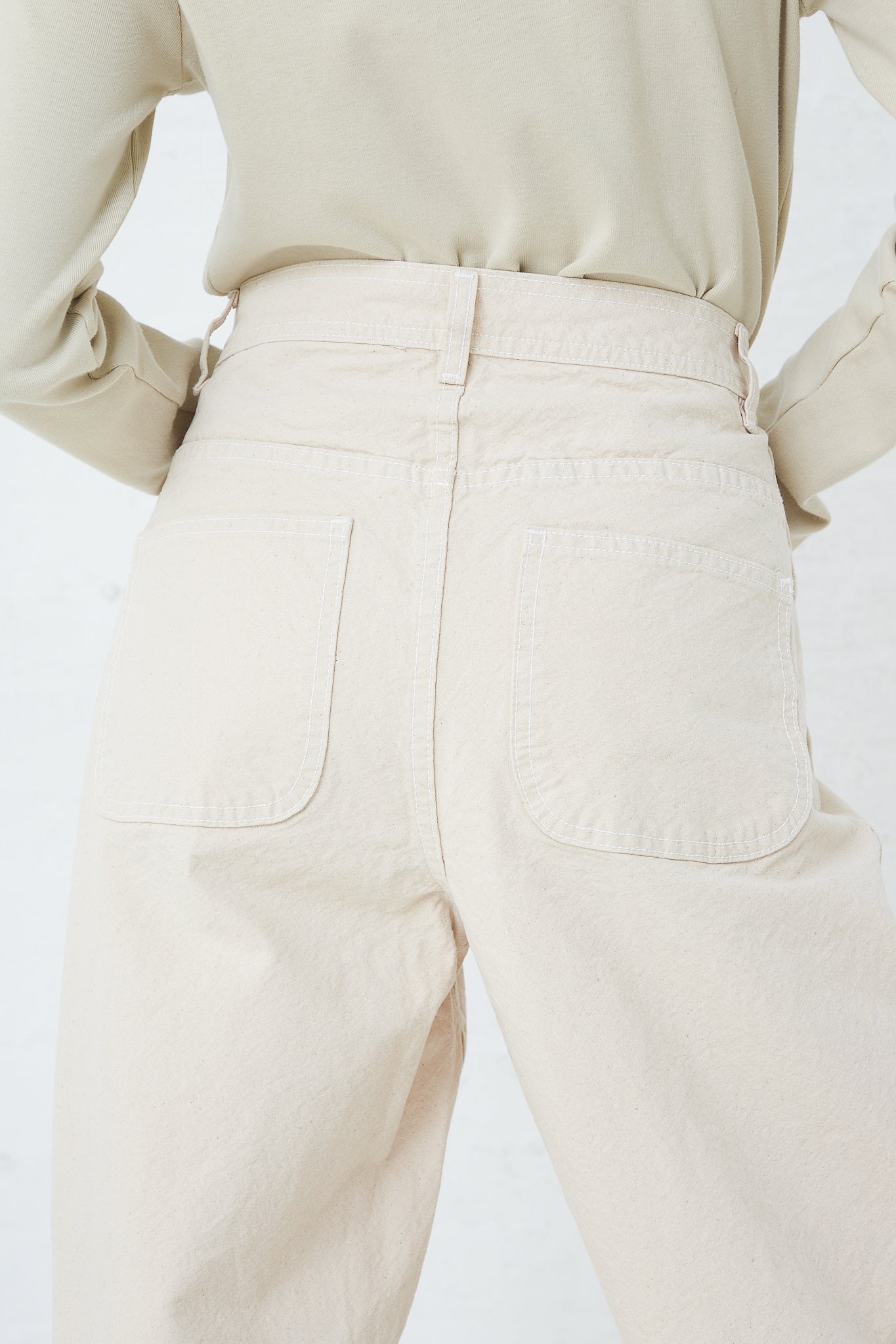 The back view of a woman wearing Jesse Kamm's Organic Canvas California Wide in Natural beige pants made from organic cotton.