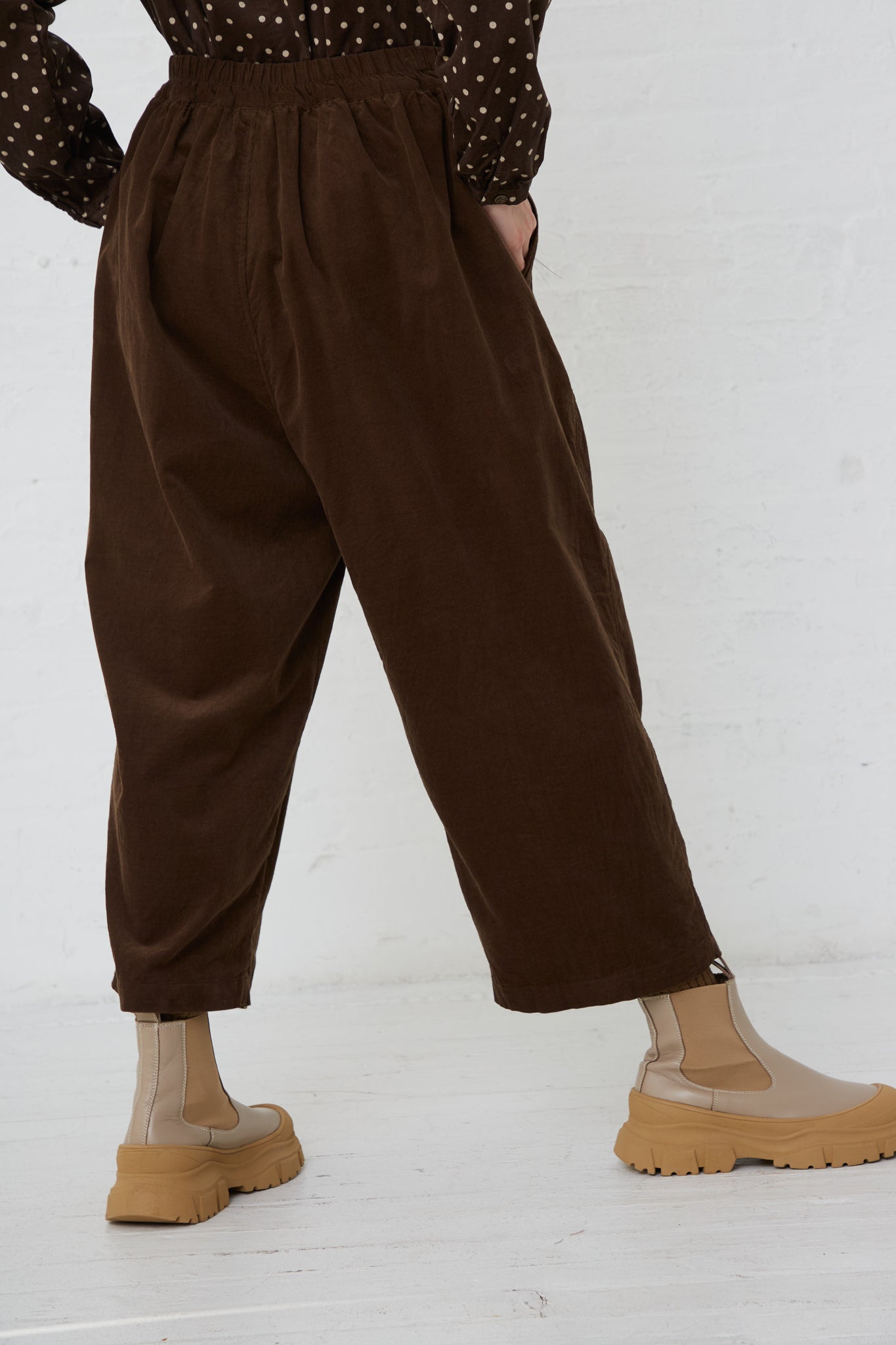 A woman wearing Ichi's Cotton Pant in Brown with a relaxed fit. Back view. Hand in pocket.