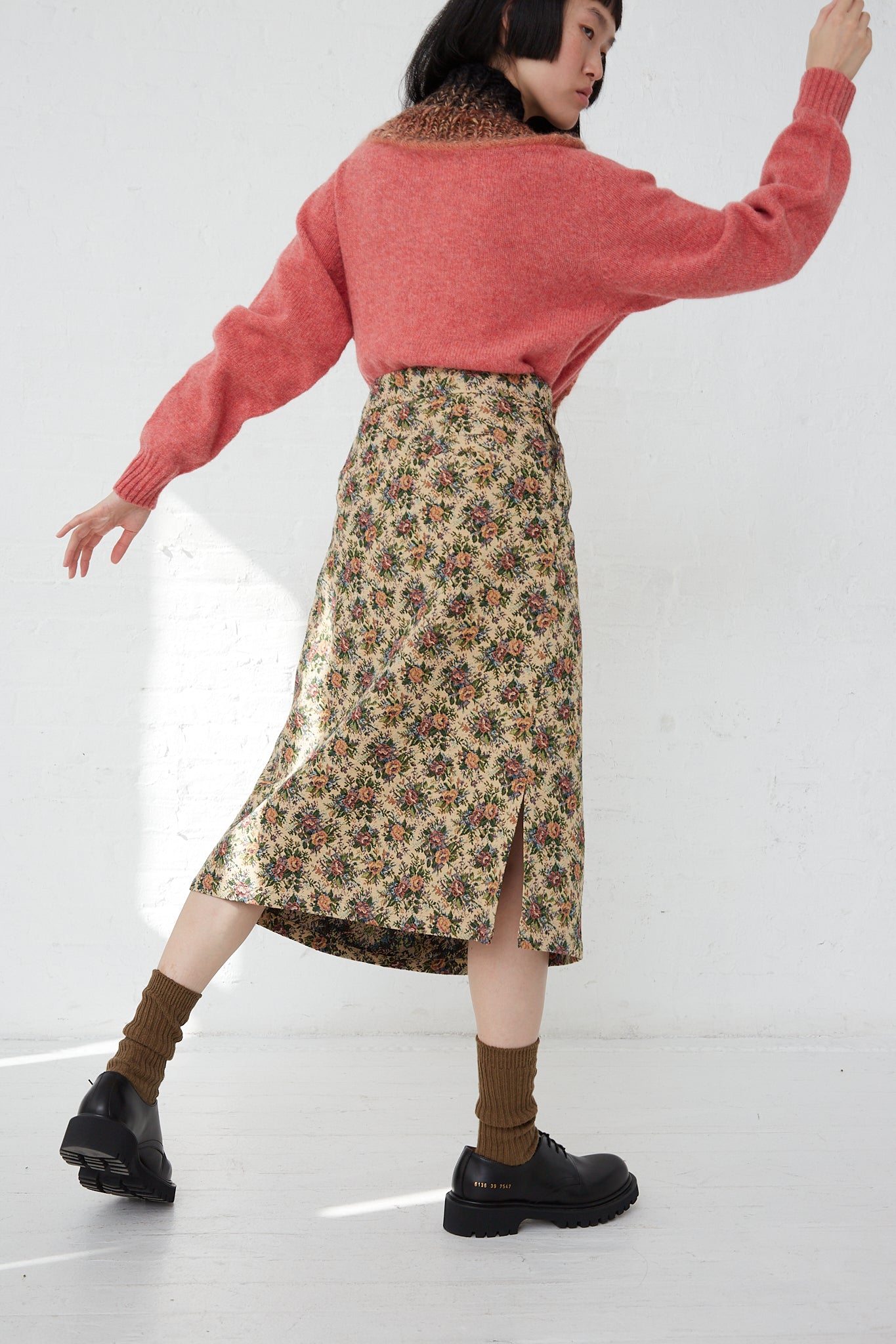 A woman in Bless's SMLXL Skirt No. 75 in Flower and a luxury lifestyle brand's pink sweater.