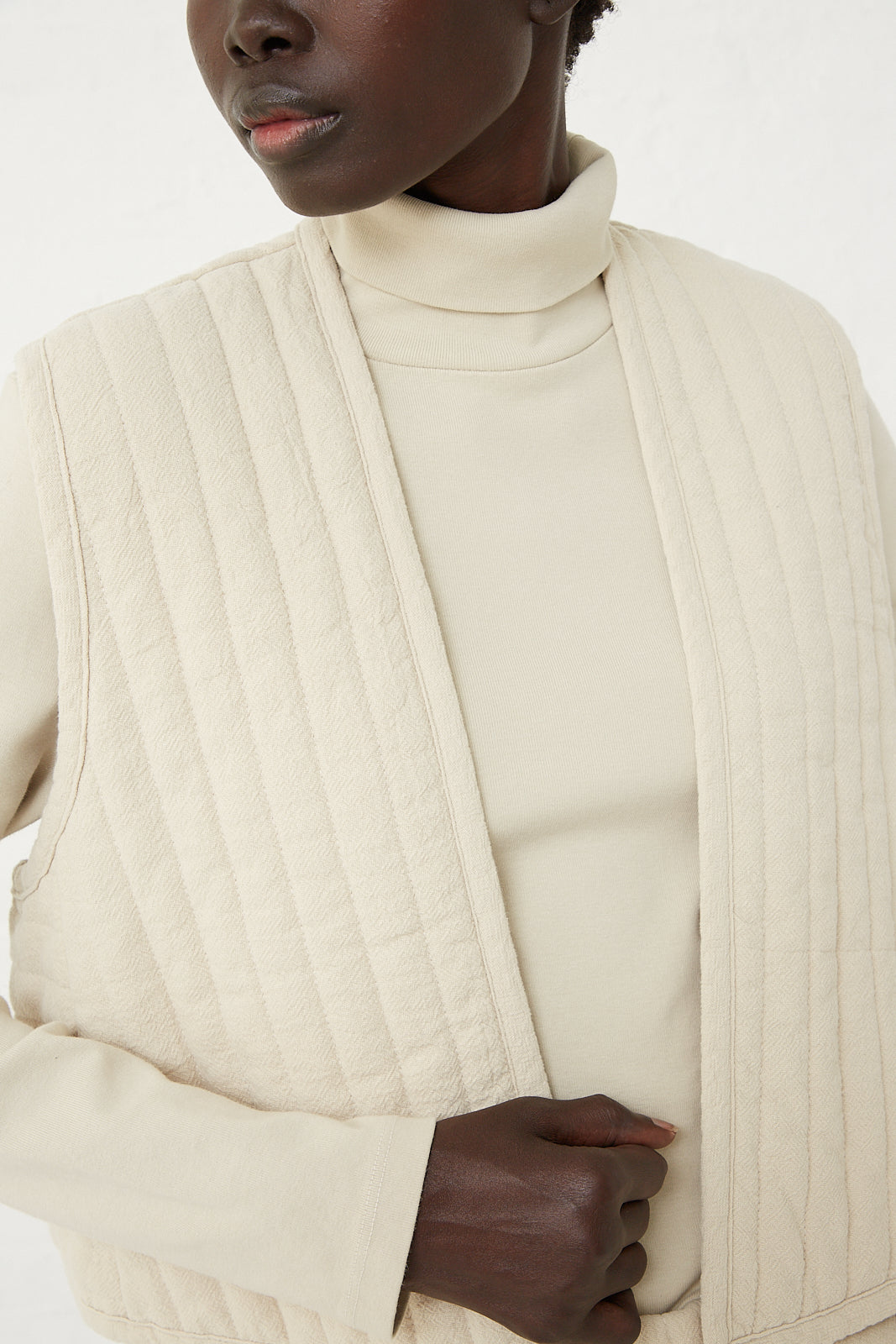 A quilted vest in ivory worn by a black woman, created by the Los Angeles-based label Black Crane.