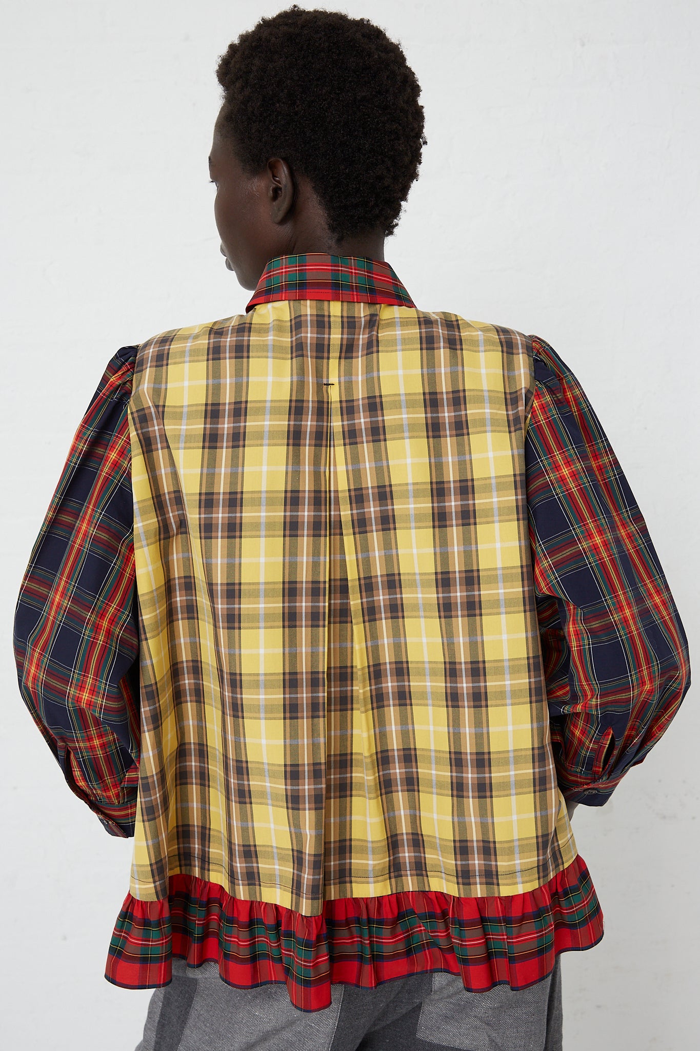 The back view of a woman wearing a KasMaria Cotton Poplin Ruffle Shirt in Mix Plaid.