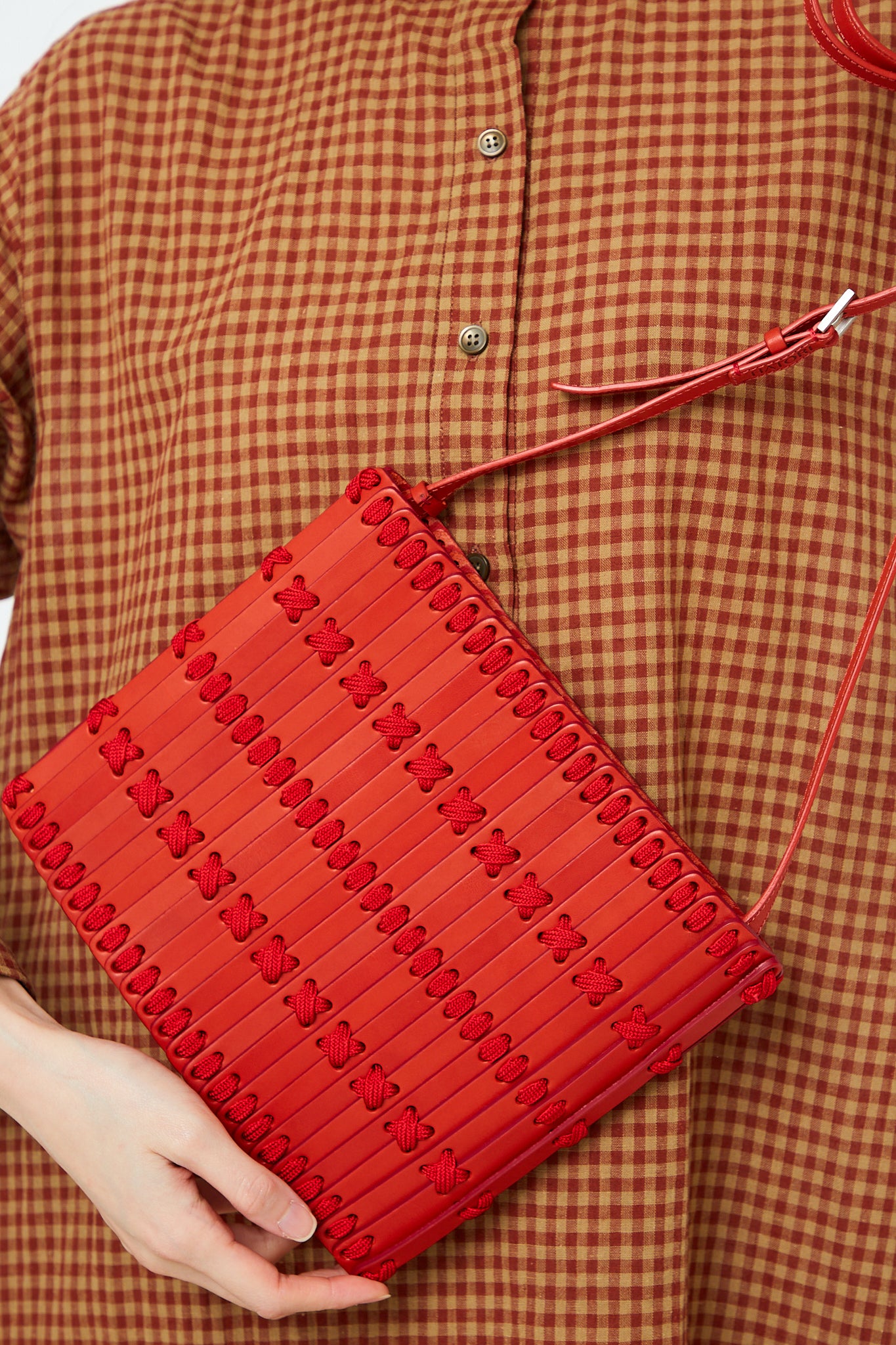 A woman is holding a Hatori handcrafted Crossbody Bag 46 in Amaranto and Ruby.