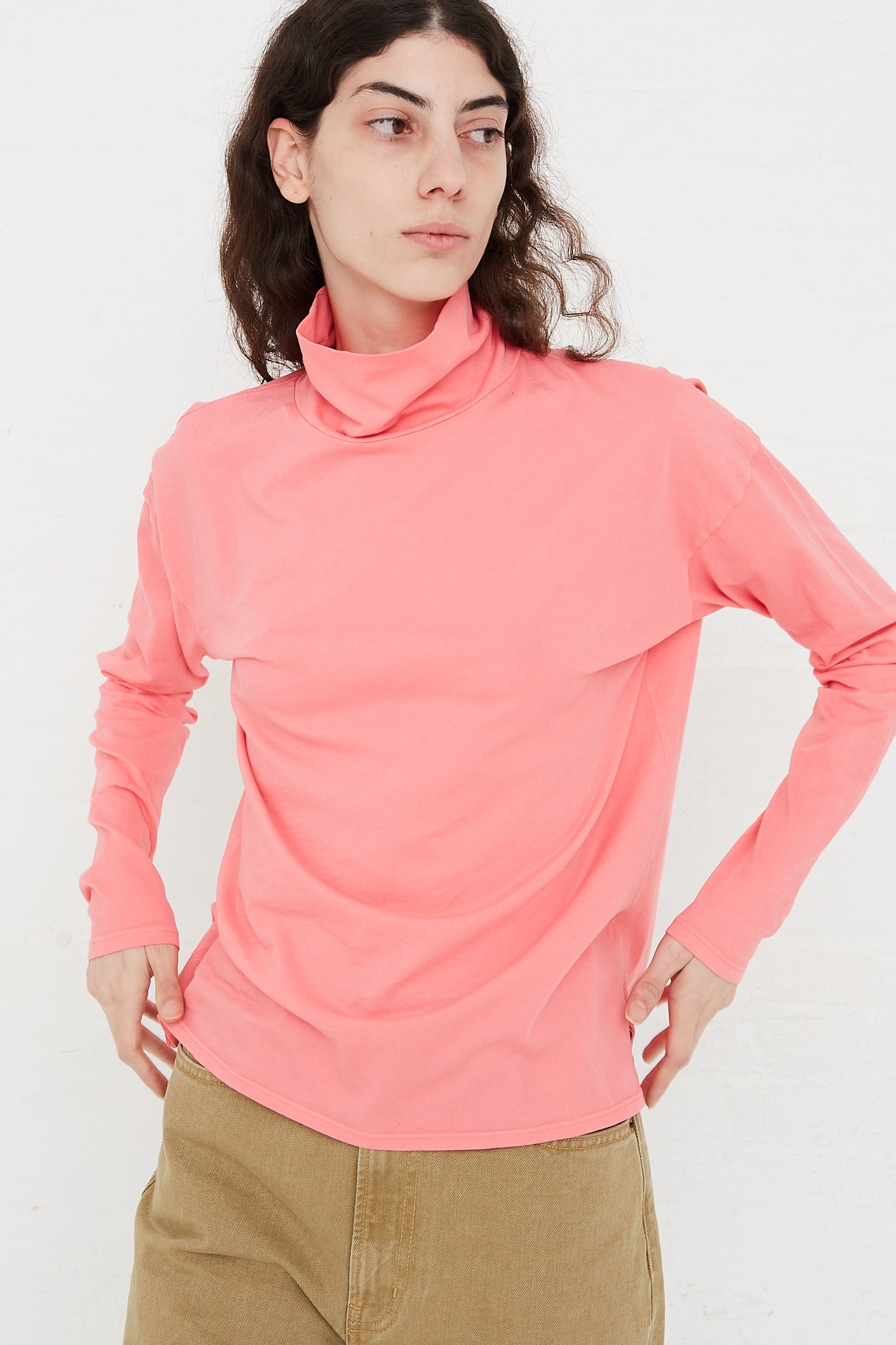 The model is wearing a Cotton Turtleneck Shirt in Calla Pink from the B Sides brand.