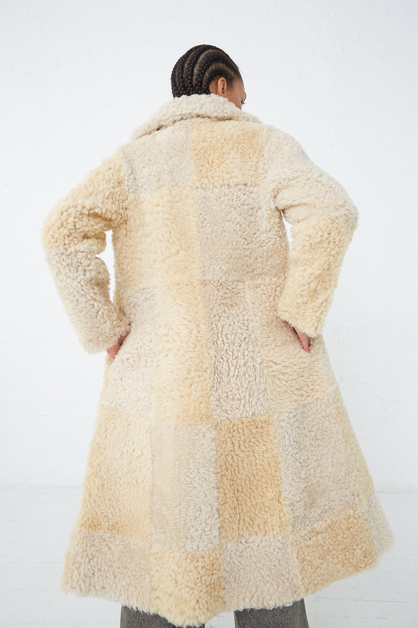 The back of a woman wearing a Milena Silvano handmade beige Sheepskin Albizia Coat in Tonal.