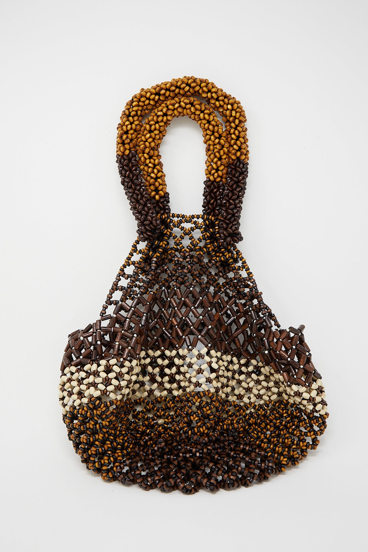 A Luna Del Pinal Medium Wooden Beaded Bag in Bone Brown with brown and white wooden beads on a white surface.