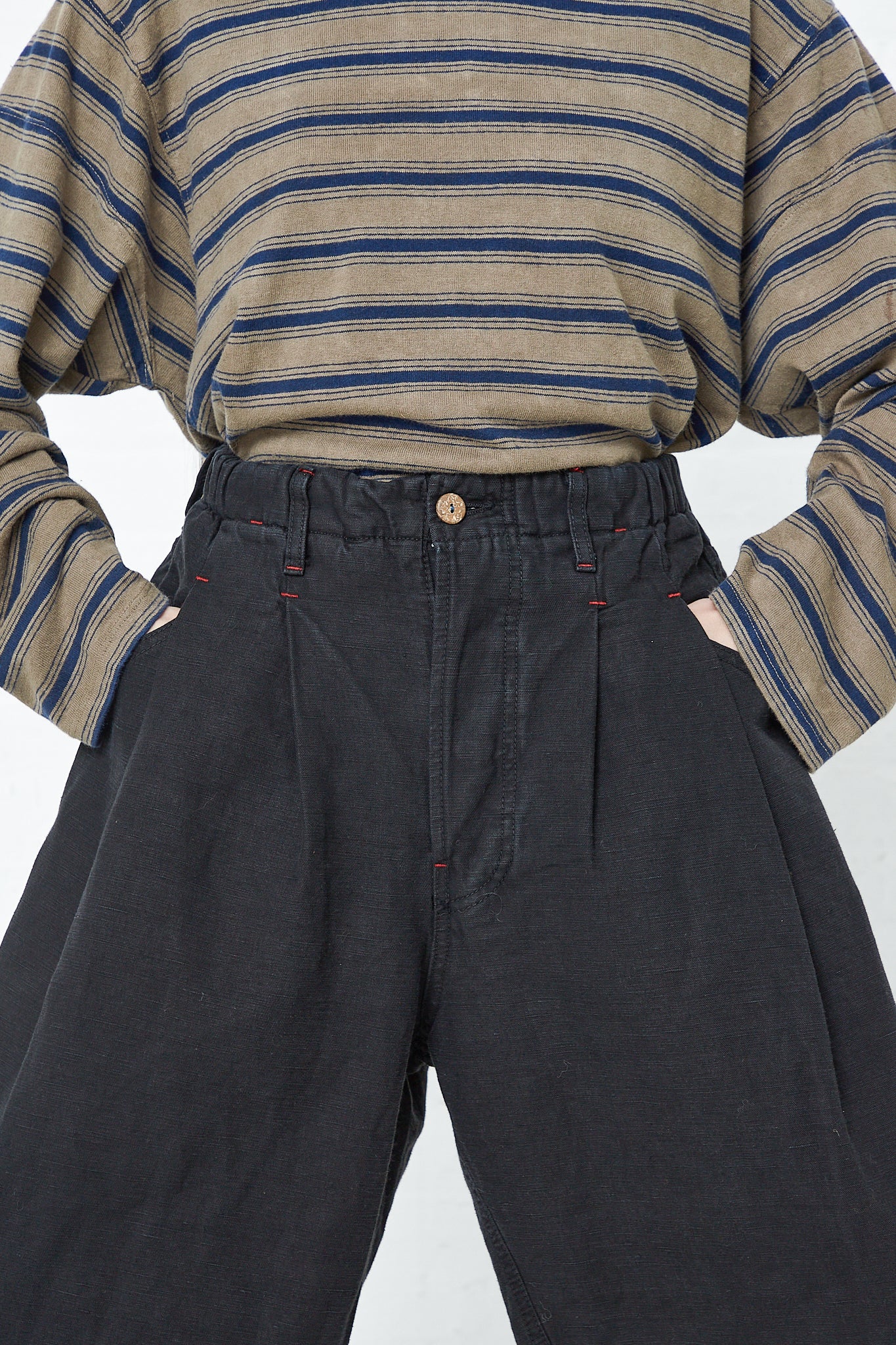 A man in Dr. Collectors' 9 oz. Cotton and Hemp P40 Z Boys Military Pant in Sulfur Black and a striped t-shirt.