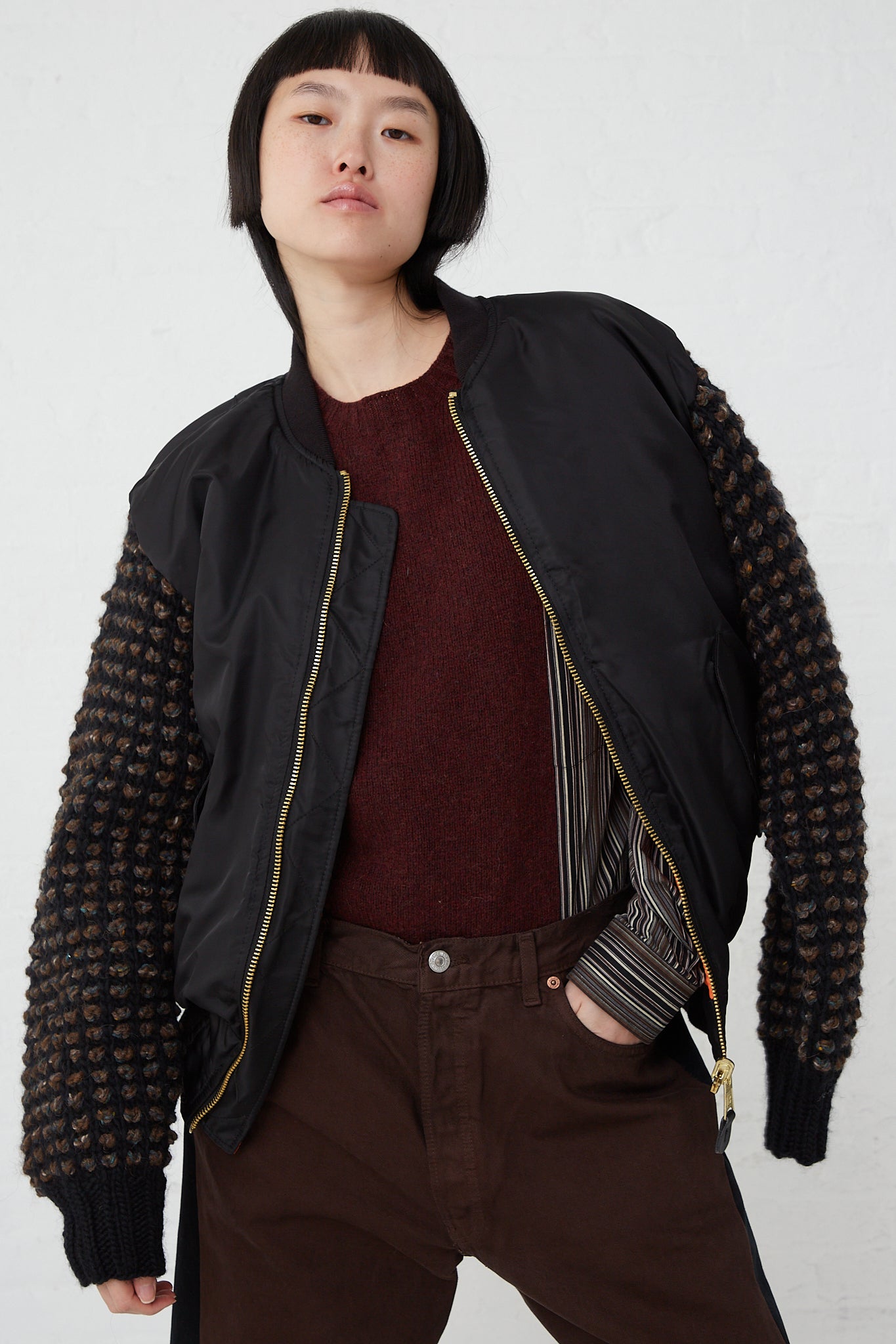 A woman wearing an oversized fit black Sleeve Bomber No. 70 in Black made by Bless, paired with brown pants.
