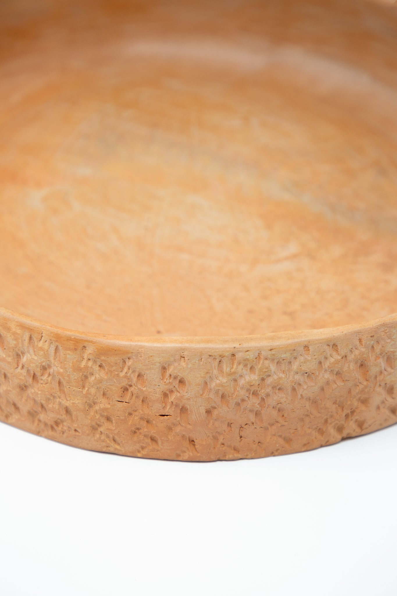 A Plaza Bolivar Julia Frutero Platter in Red Clay on a white surface. Up close view of clay texture.