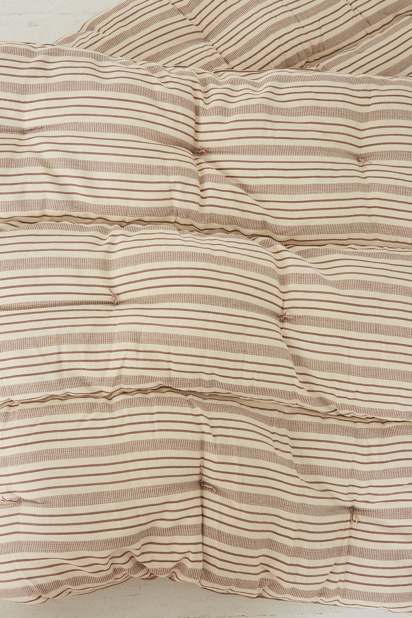 A Tensira Tufted Overlay Mattress in Chocolate Brown and Off White Stripe.