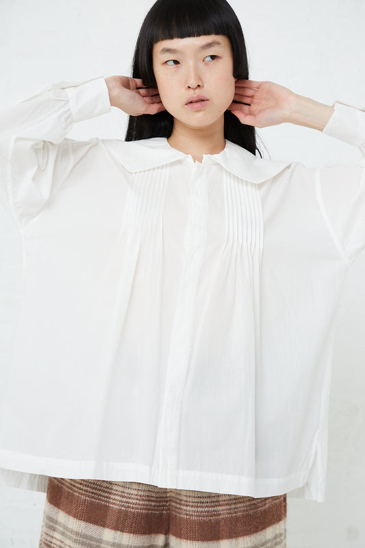A woman wearing Toujours' Square Collar Pin Tuck Smock Shirt in White, made of fine yarn cotton.