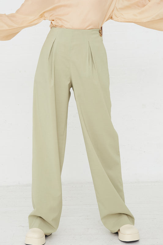A woman wearing Rejina Pyo's Reine Trouser in Sage, a minimalist trousers made of a sage green polyester silk blend. Front view.