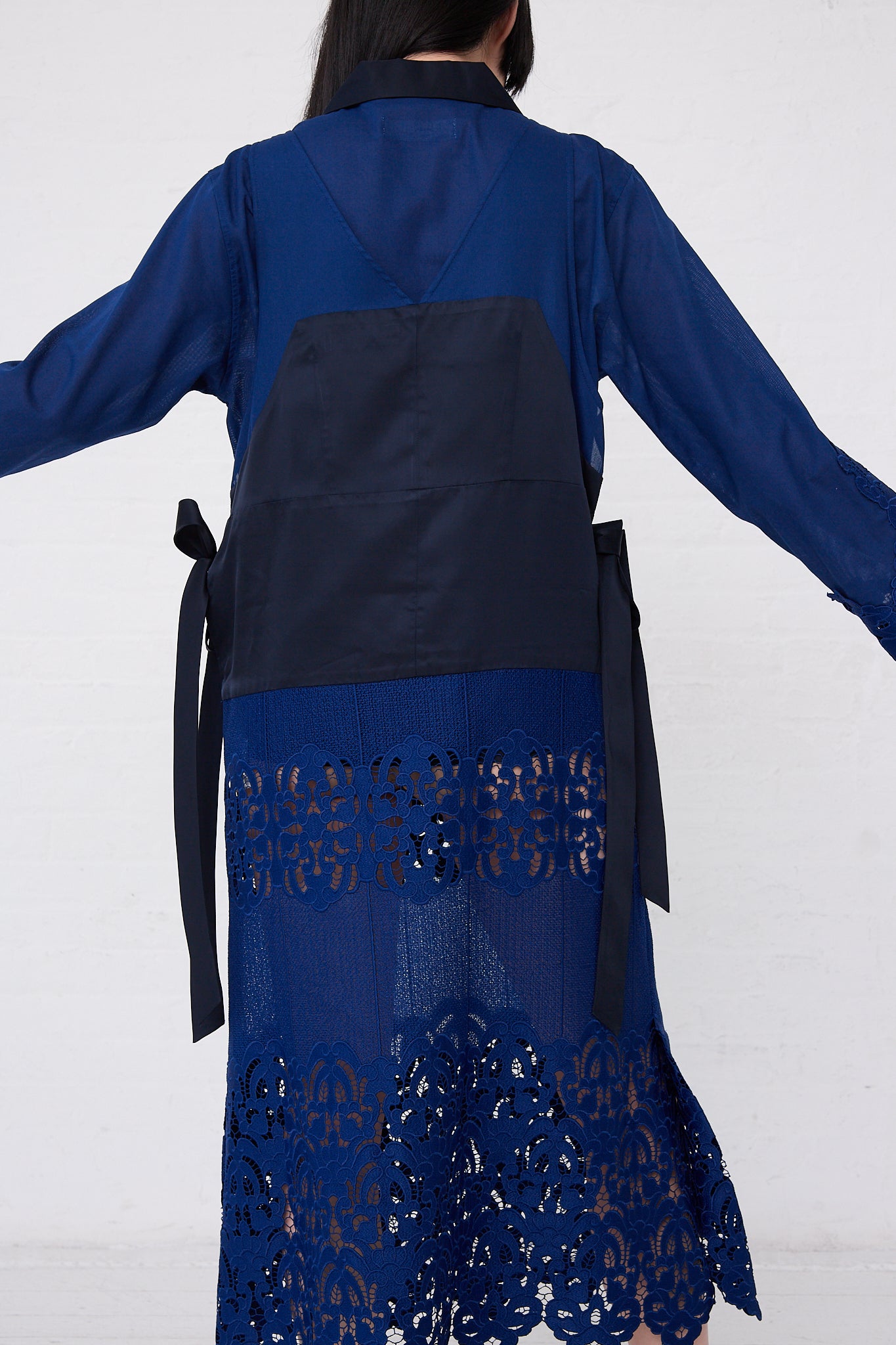 The back view of a woman wearing a TOGA PULLA Mesh Lace Dress in Blue.