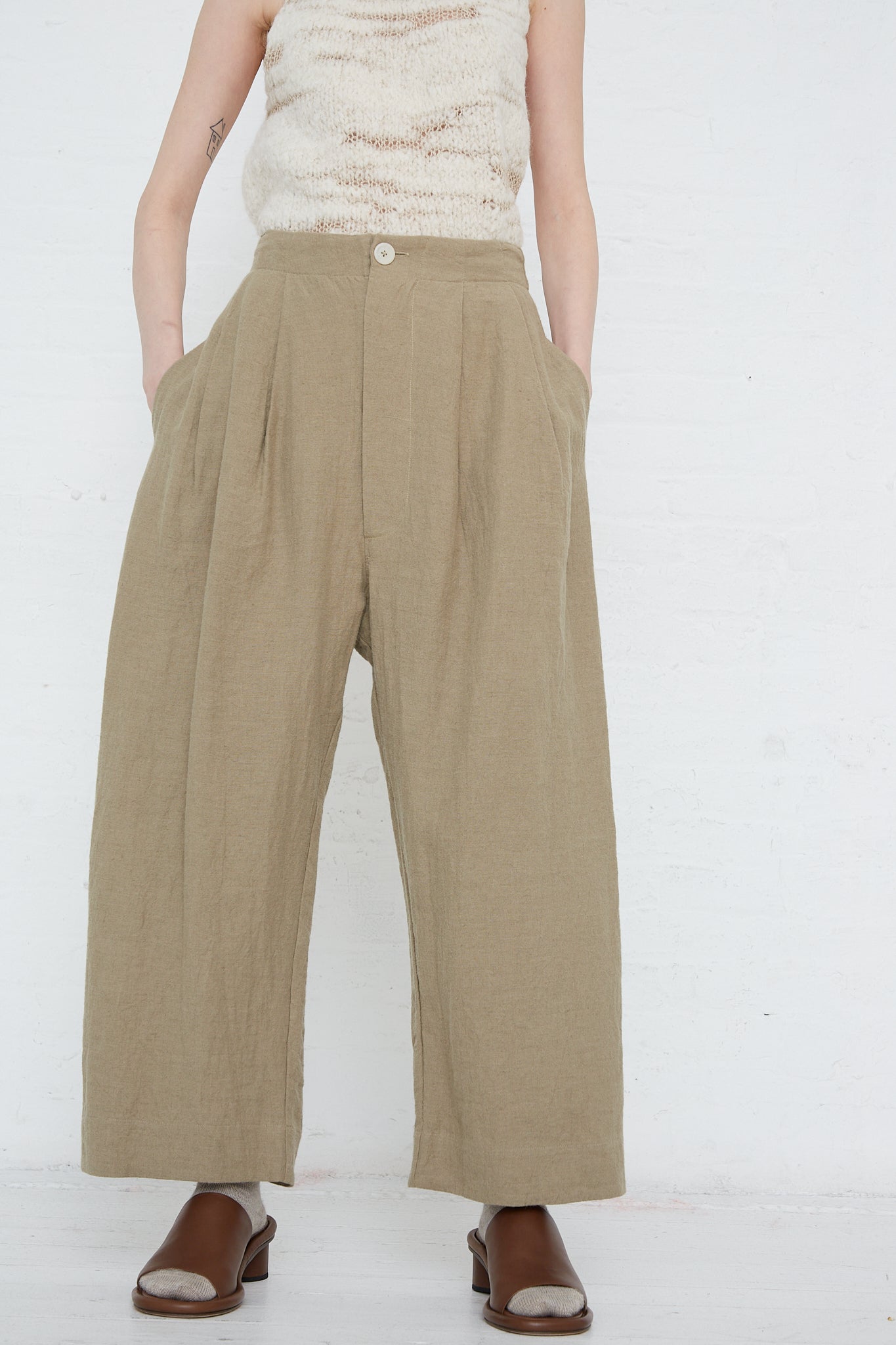 A woman wearing the Lauren Manoogian Linen and Wool Como Trouser in Clay wide leg khaki pants and a white top.
