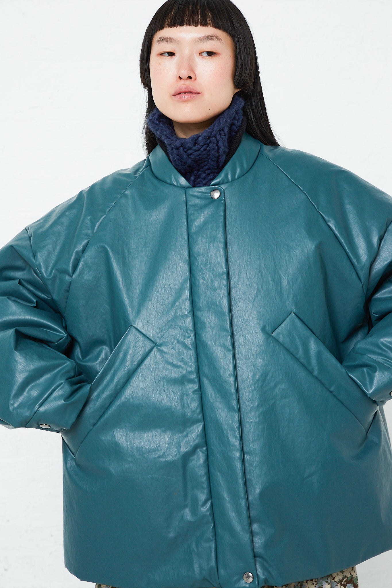 A model wearing an oversized teal leather Kassl Padded Bomber Oil Jacket in Forest.