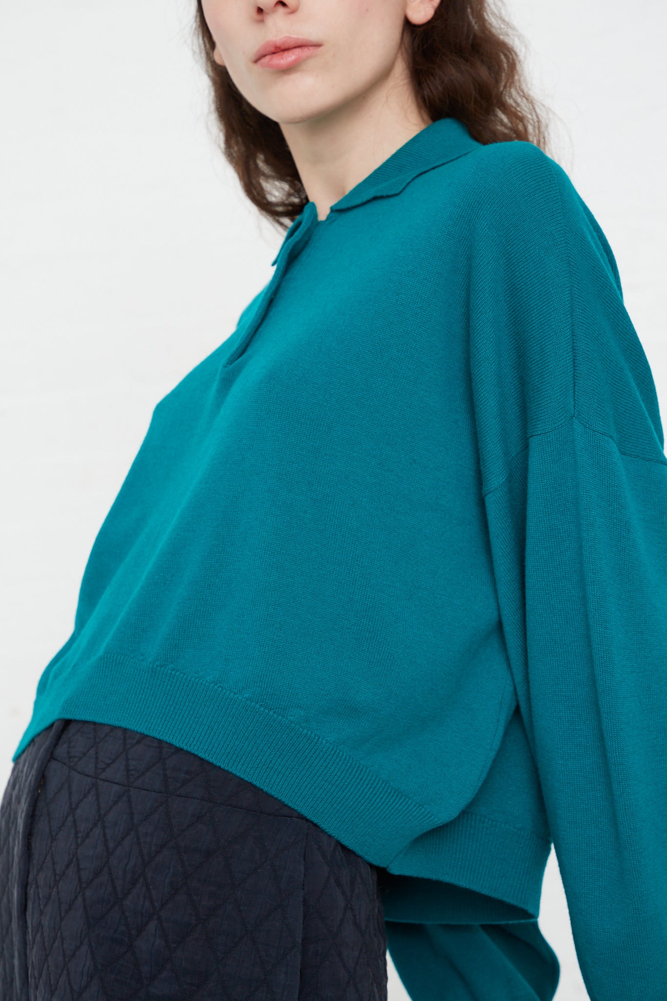 A model wearing a Cordera Merino Wool Polo Sweater in Teal Green made in Spain.