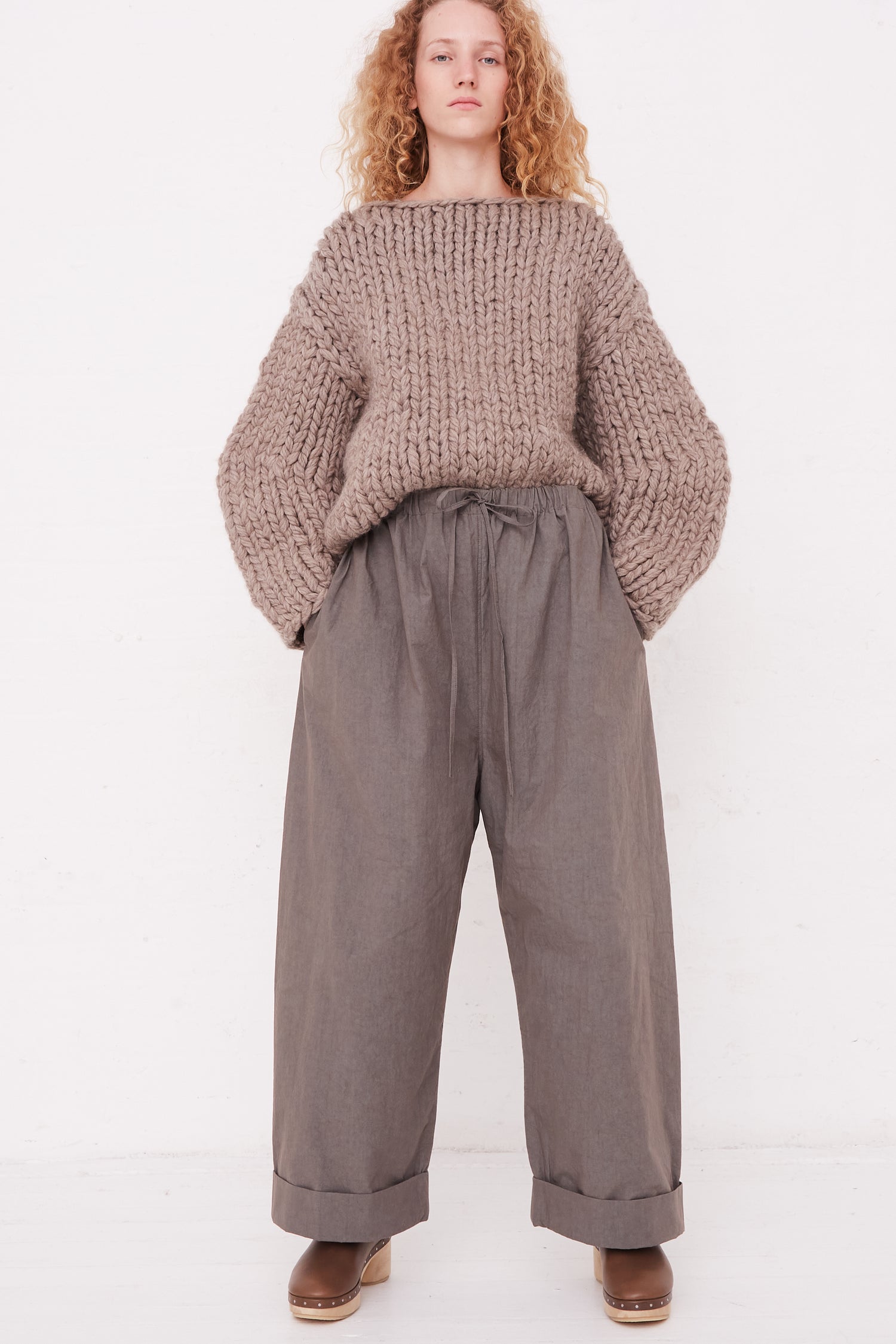 A woman in Lauren Manoogian's Duvet Pant in Lead and a sweater with an elasticated waist.