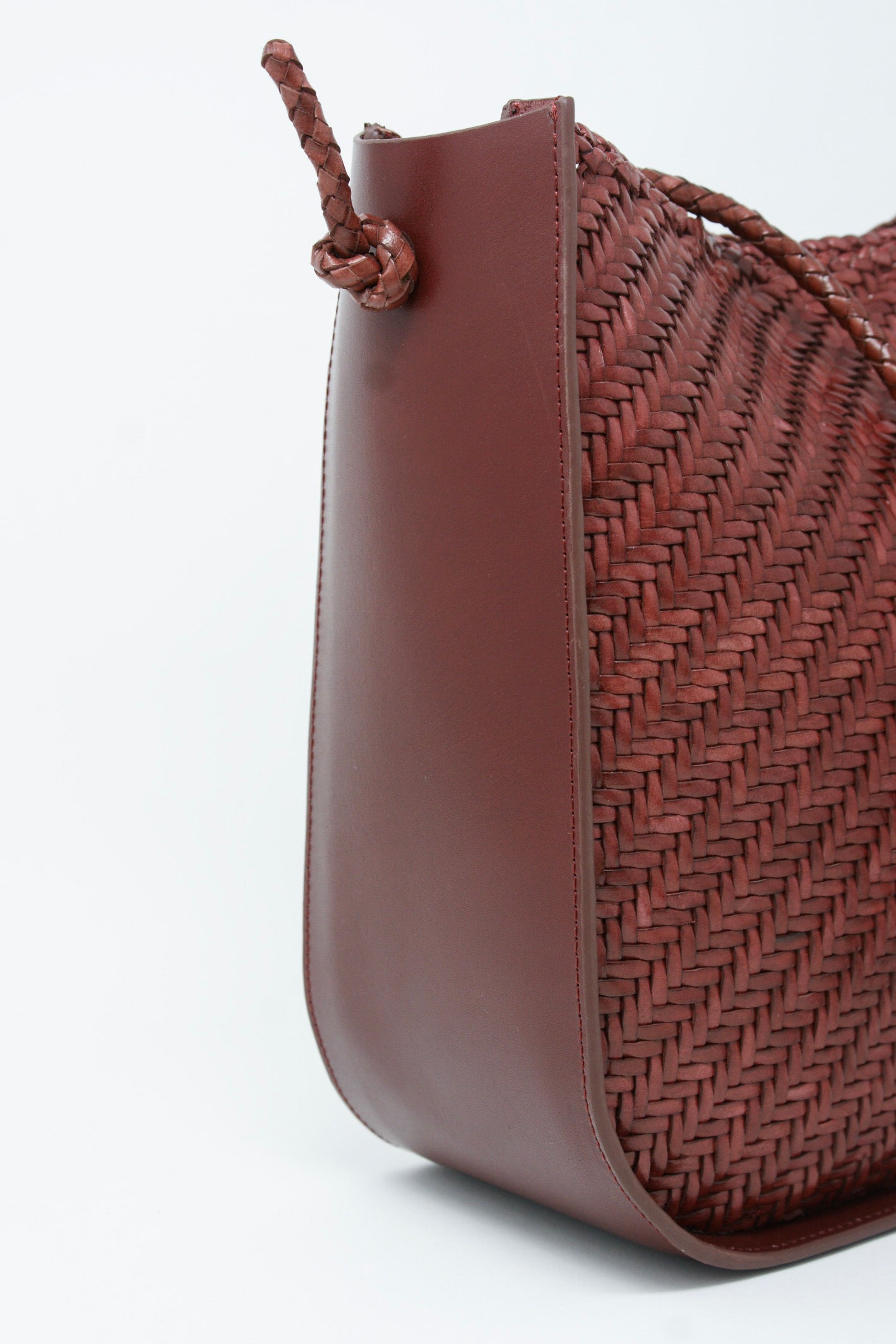 A Dragon Diffusion Wanaka Crossbody Bag in Bordo on a white surface.
