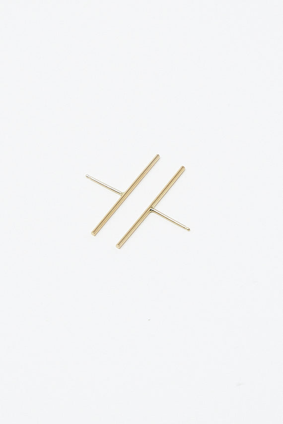 A pair of Stick Stud 1" Single Earrings in 14K Yellow Gold by Kathleen Whitaker on a white surface.