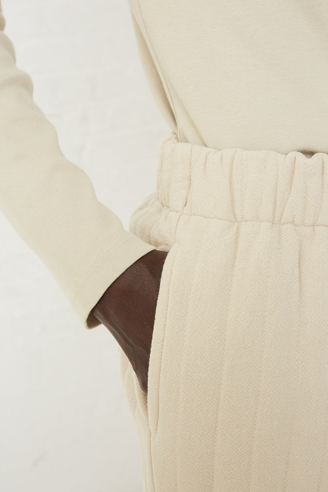 A woman wearing an ivory turtleneck and quilted easy pants in ivory made by Black Crane.