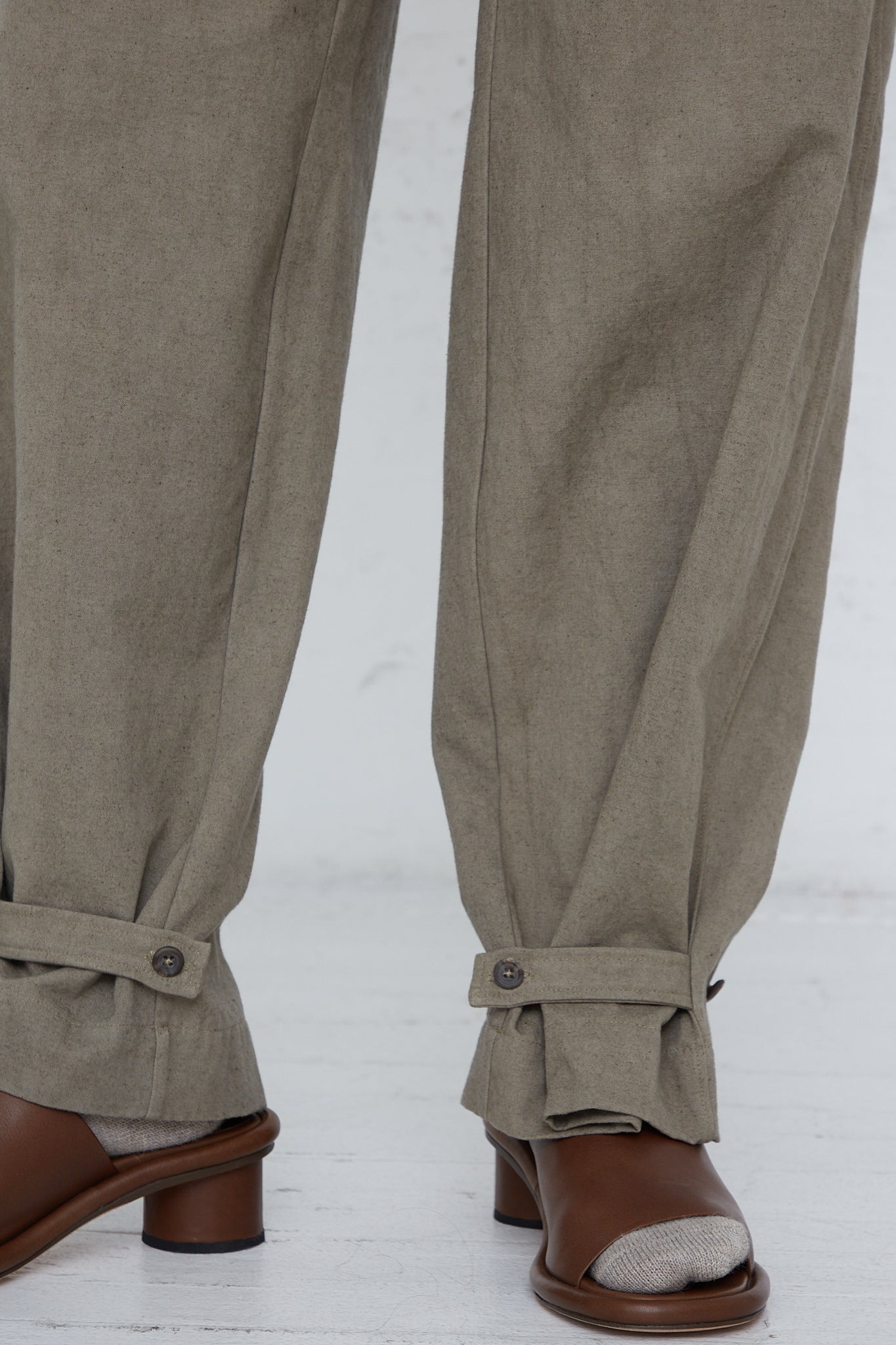 The legs of a woman wearing Lauren Manoogian Belted Trouser in Fatigue pants and brown sandals.