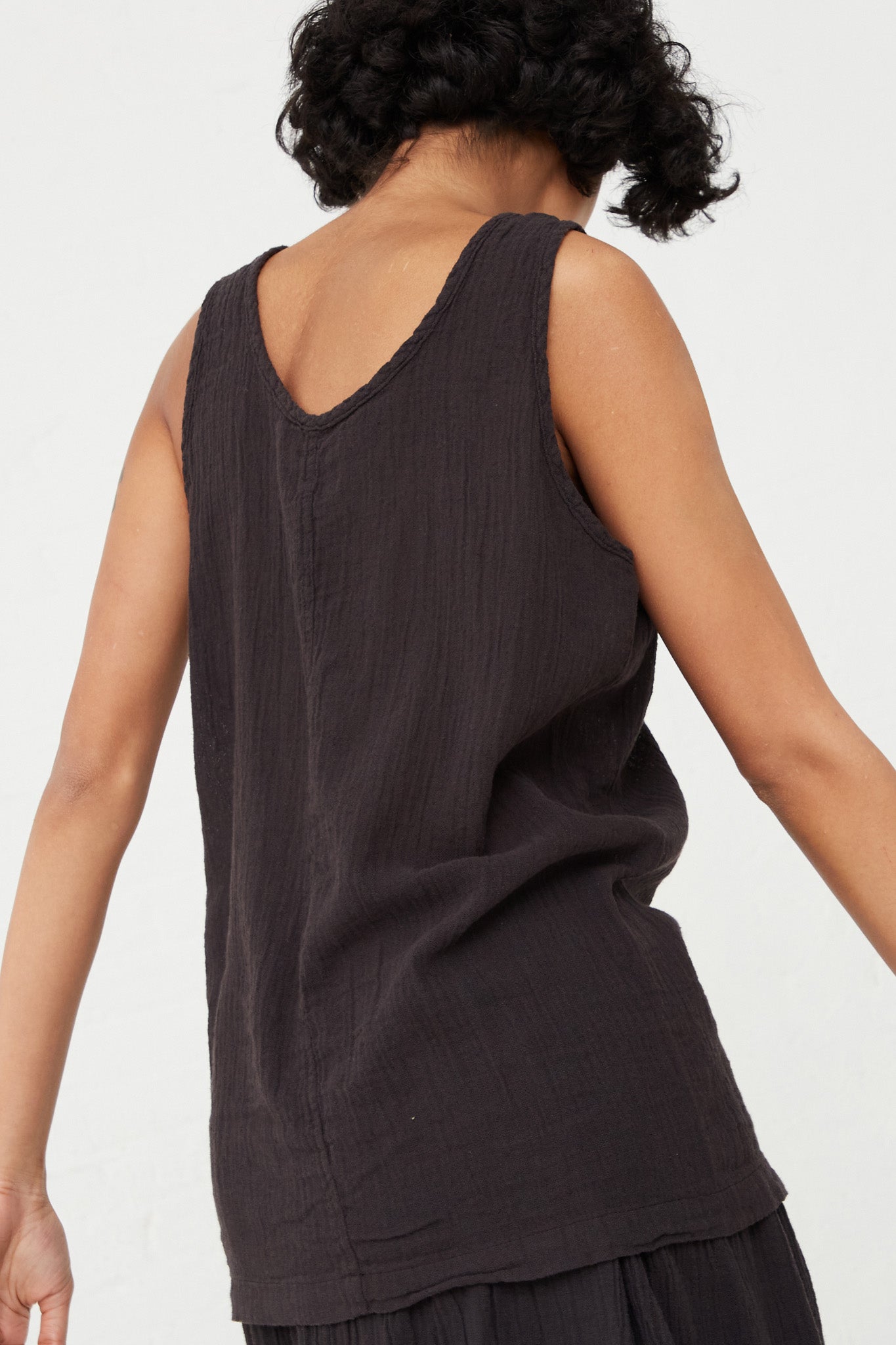 The back view of a woman wearing a Black Crane scoop neck cotton linen blend Tank Top in Black. Up close.