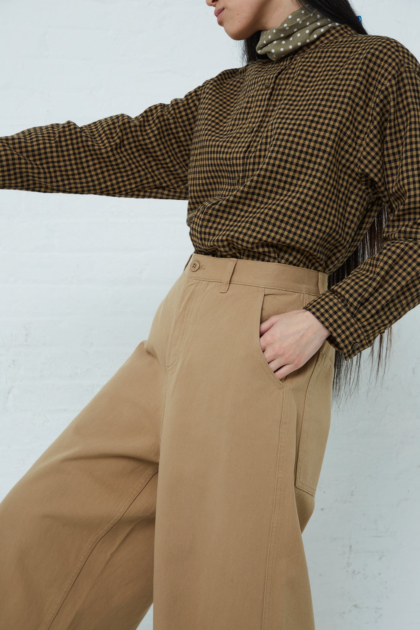 A woman in Ichi's cotton pant in beige and a checkered shirt.