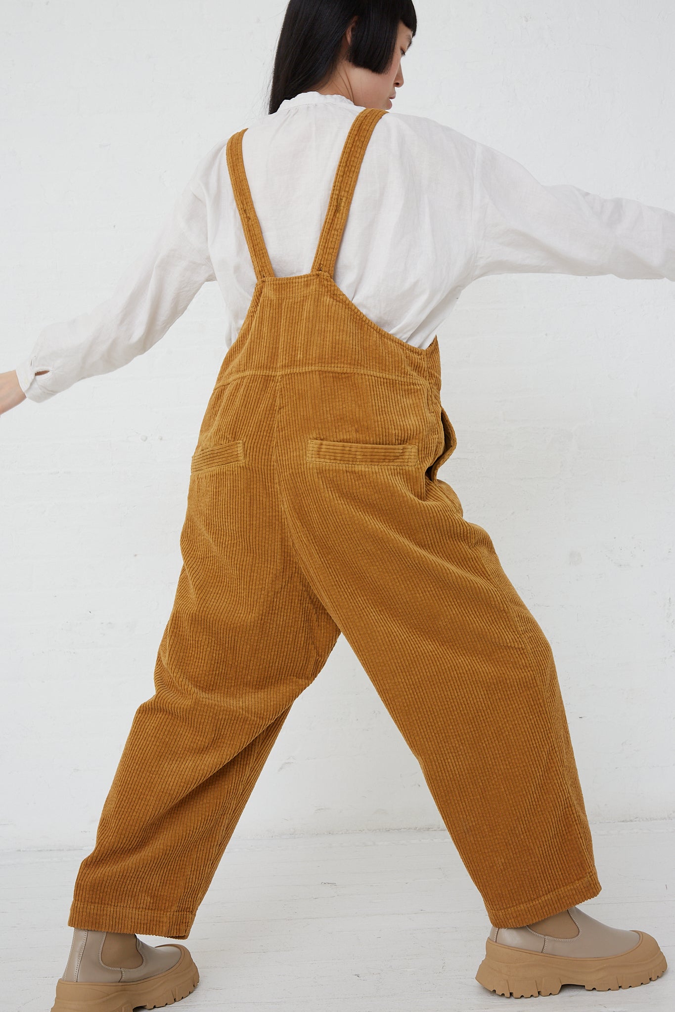 A nest Robe Cotton Corduroy Overall in Camel woman wearing a white shirt made of cotton.