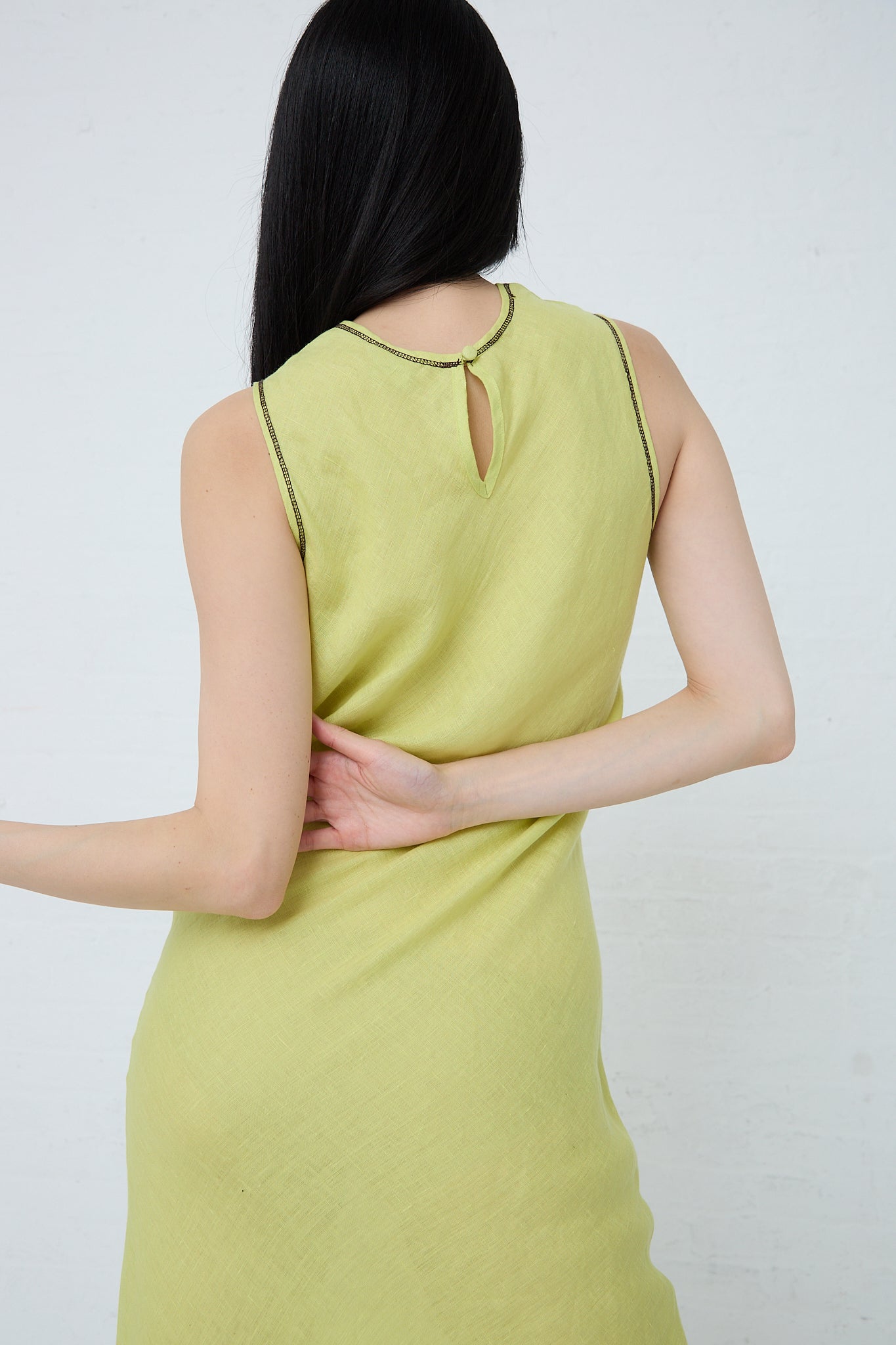 A sustainably produced Baserange woman wearing a green Linen Dydine Tank Dress in Lime with a back view.