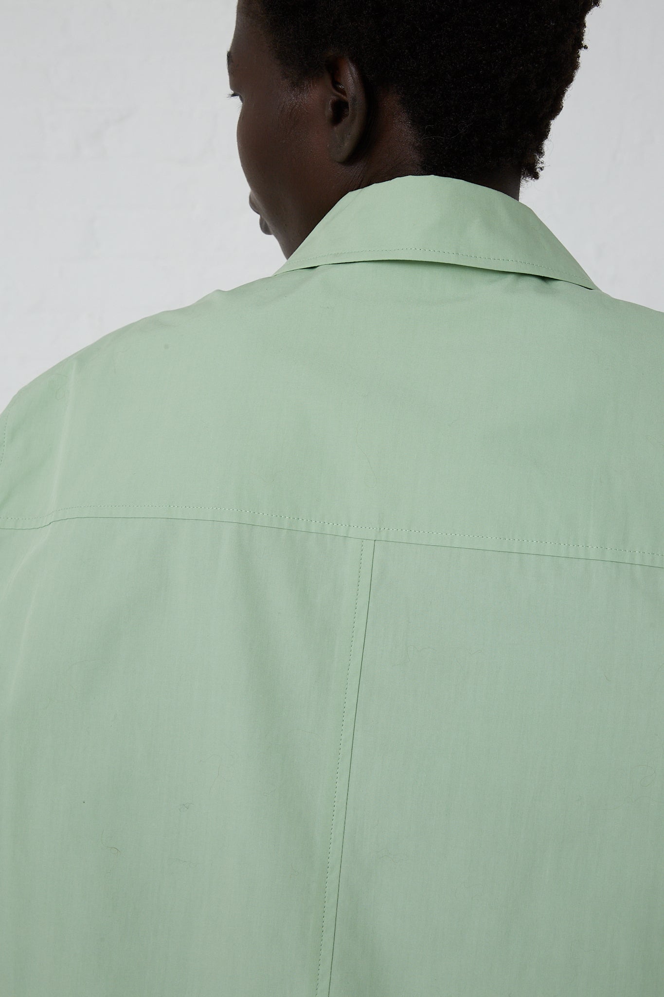 A woman wearing a Rejina Pyo Organic Cotton Caprice Shirt in Mint with a front button closure.