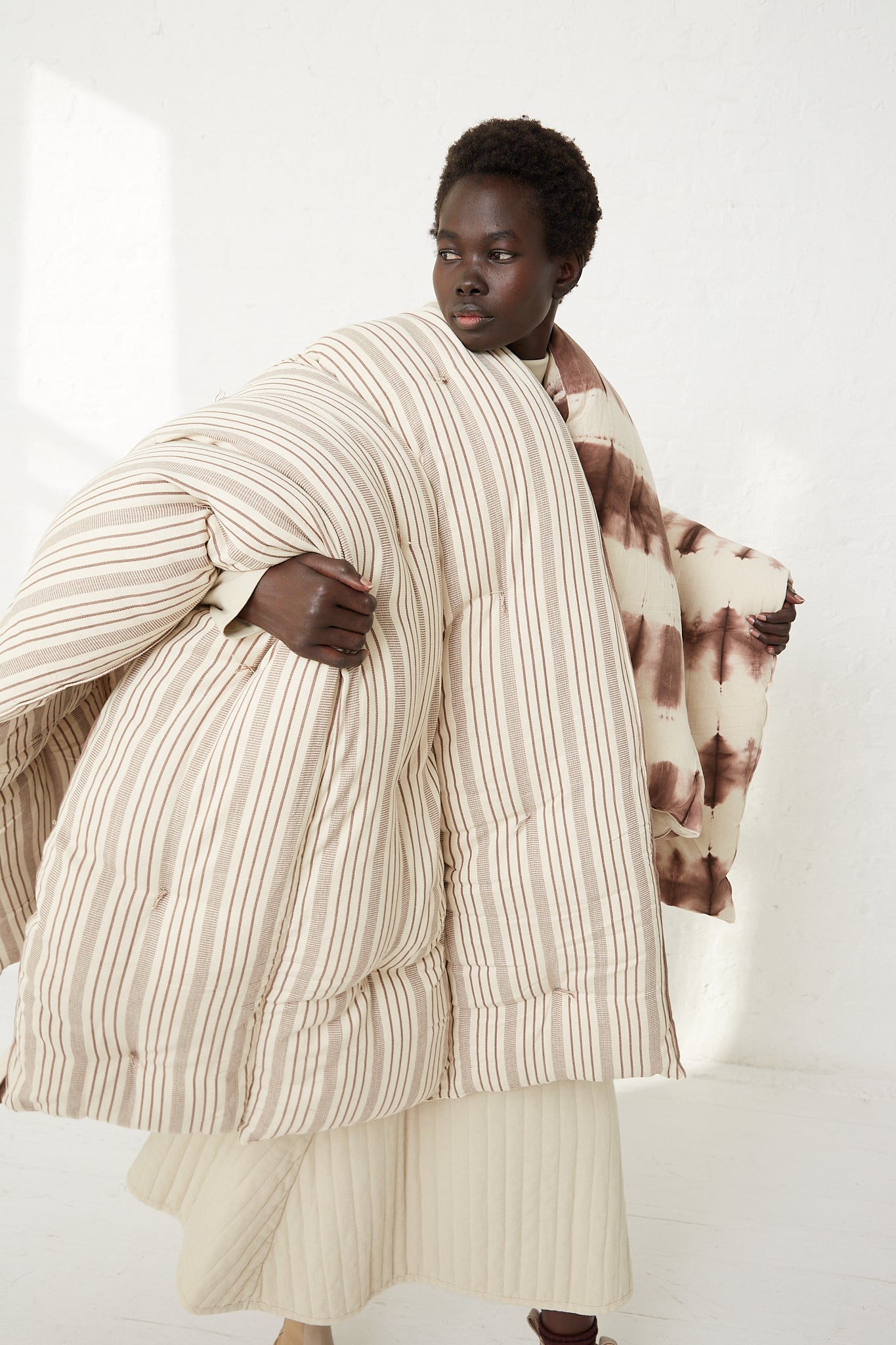 A woman wearing a Tensira striped Tufted Overlay Mattress in Chocolate Brown and Off White Stripe.