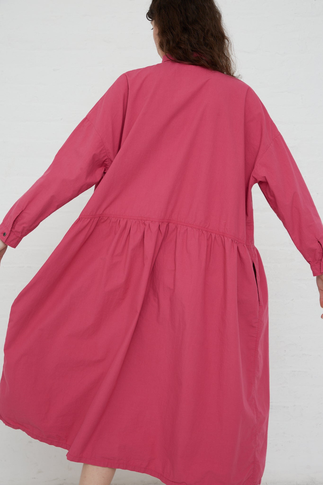The back view of a woman wearing a Woven Cotton Oumisarashi Dress in Plum raincoat from Ichi Antiquités.