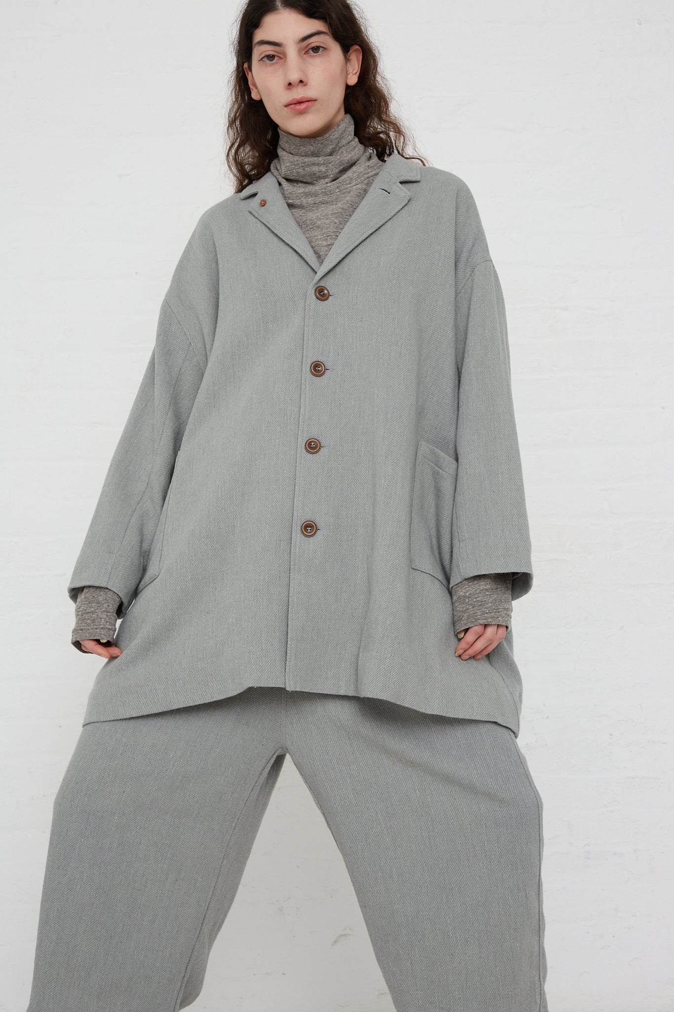 The model is wearing an oversized Merino Wool Orihimedaki Jacket in Blue by Ichi Antiquités with patch pockets.