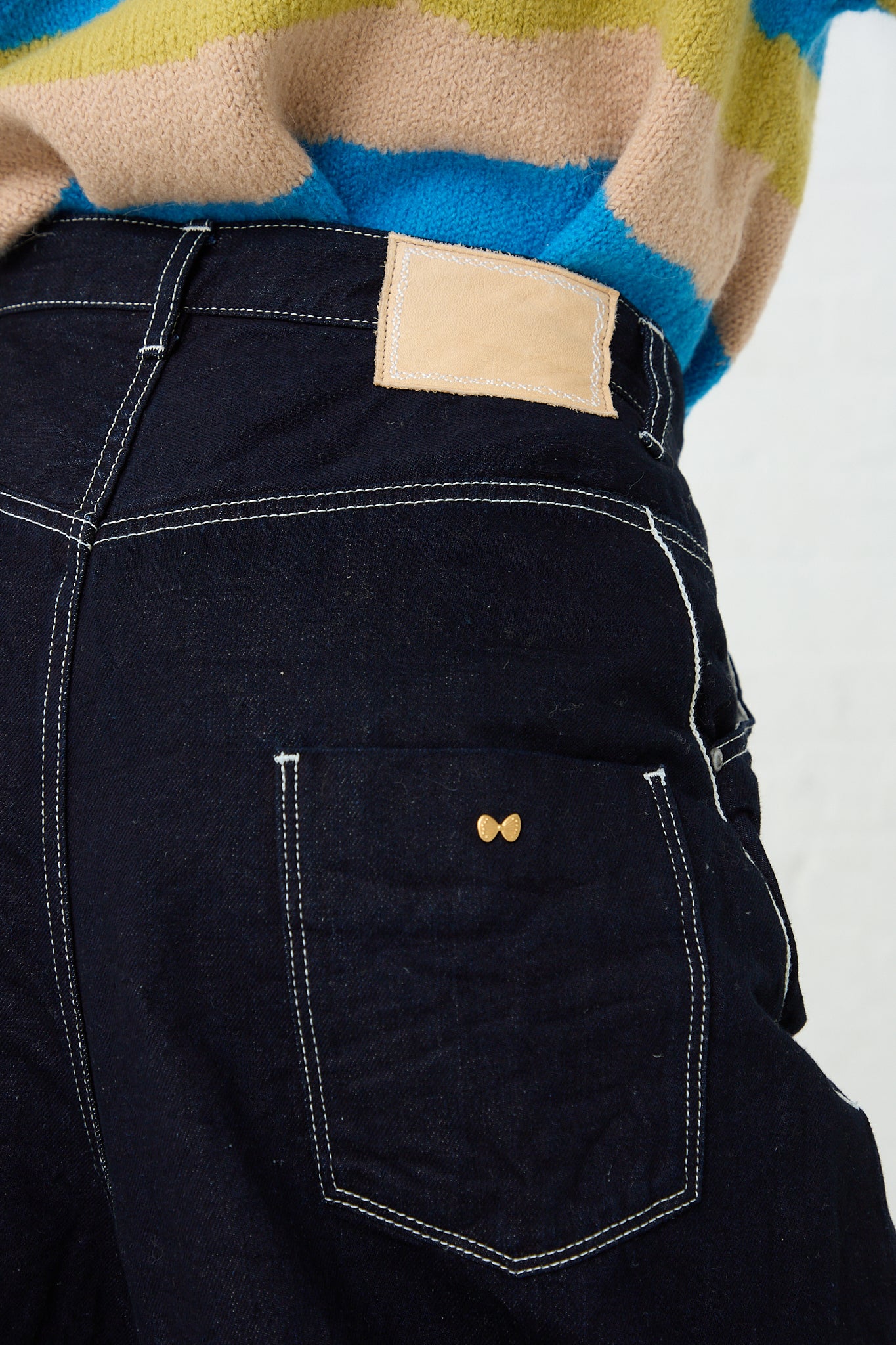 The back pocket of a person's Mina Perhonen Always Balloon Wide Pant in Indigo denim jeans. Up close view of pocket stitching and details.