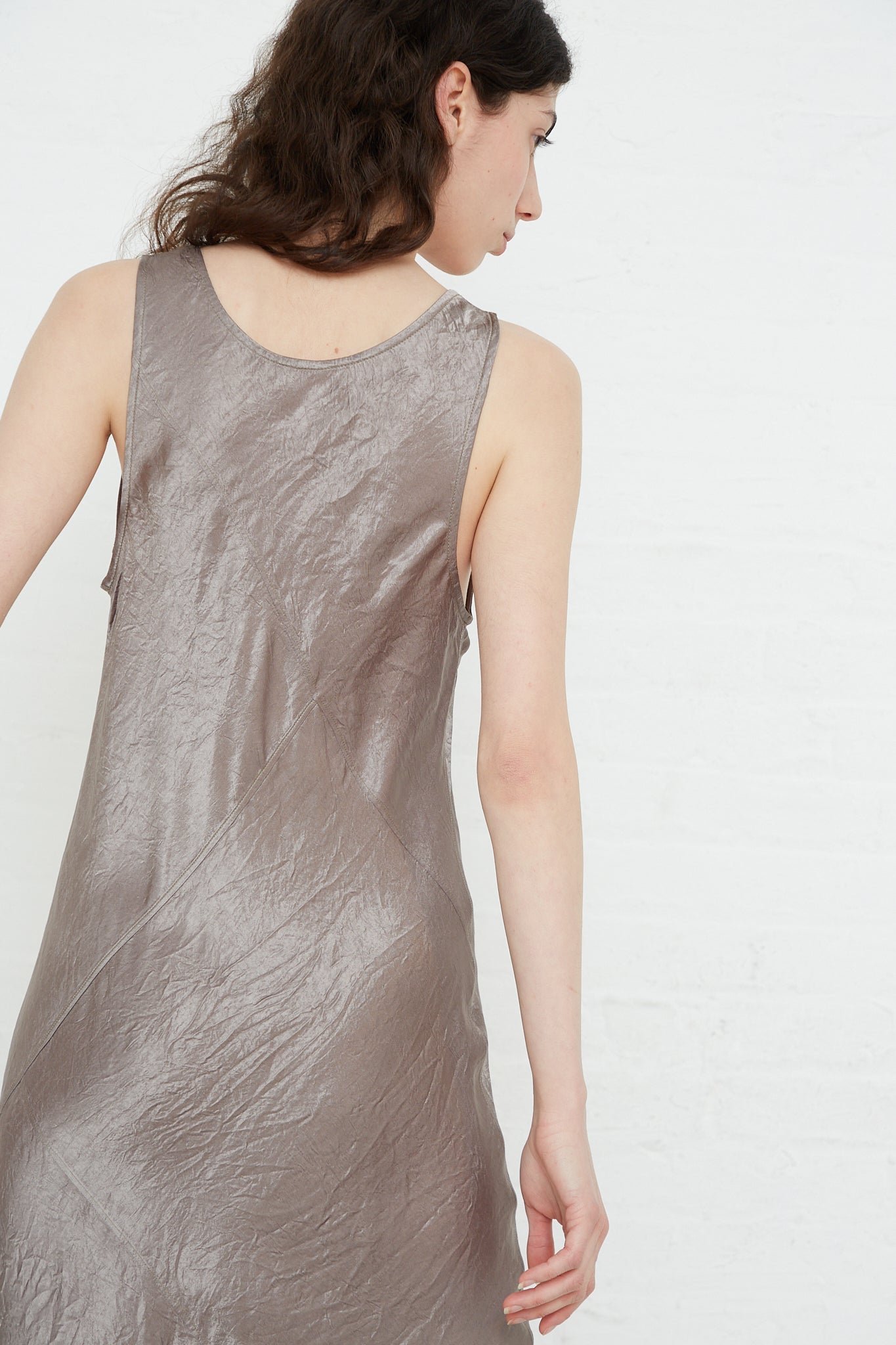 The back view of a woman wearing a Lauren Manoogian Luster Bias Dress in Laurel.