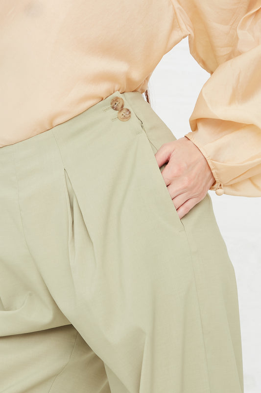 A woman wearing Rejina Pyo's Reine Trouser in Sage green and a pink blouse. Side view.