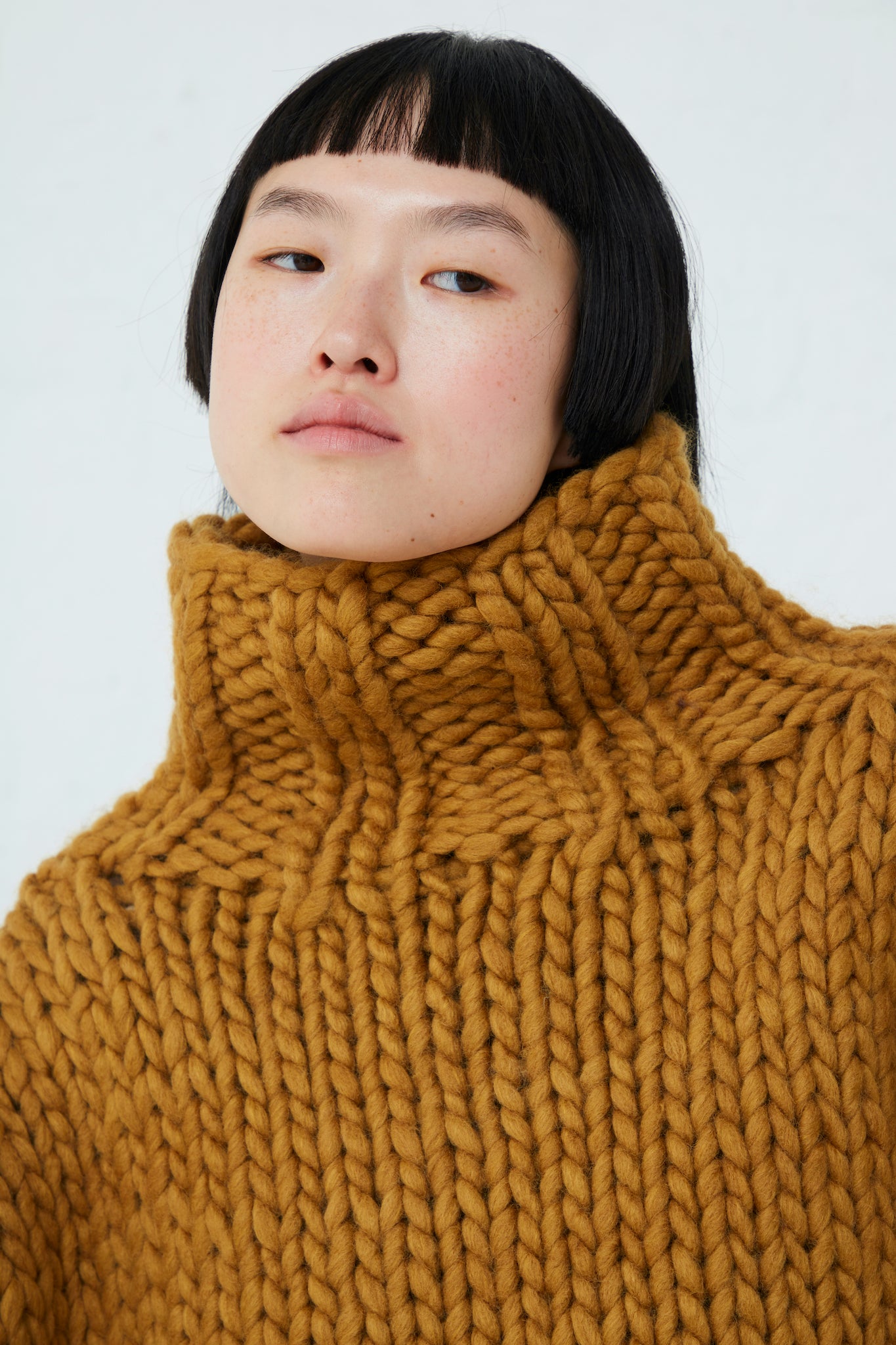 A model wearing an Ichi Wool Hand-Knit Pullover in Mustard. Up close.