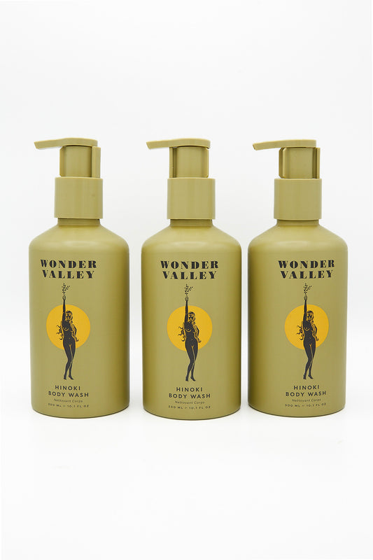 Three bottles of Wonder Valley Hinoki Body Wash with a woman's face on them.